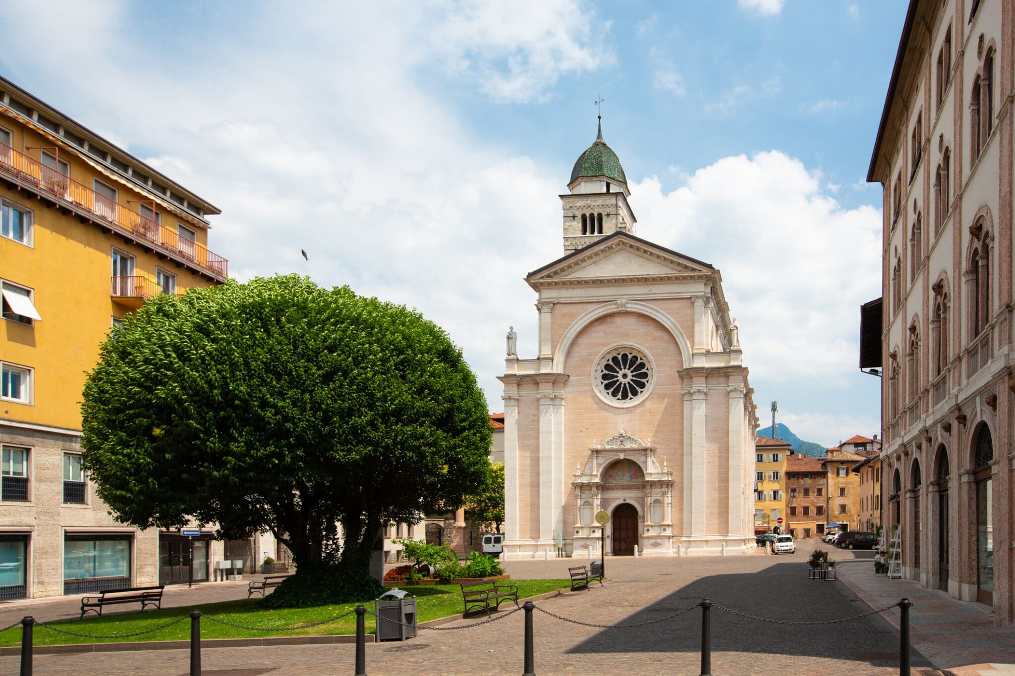 Facciata chiesa italiana con piazza alberata.