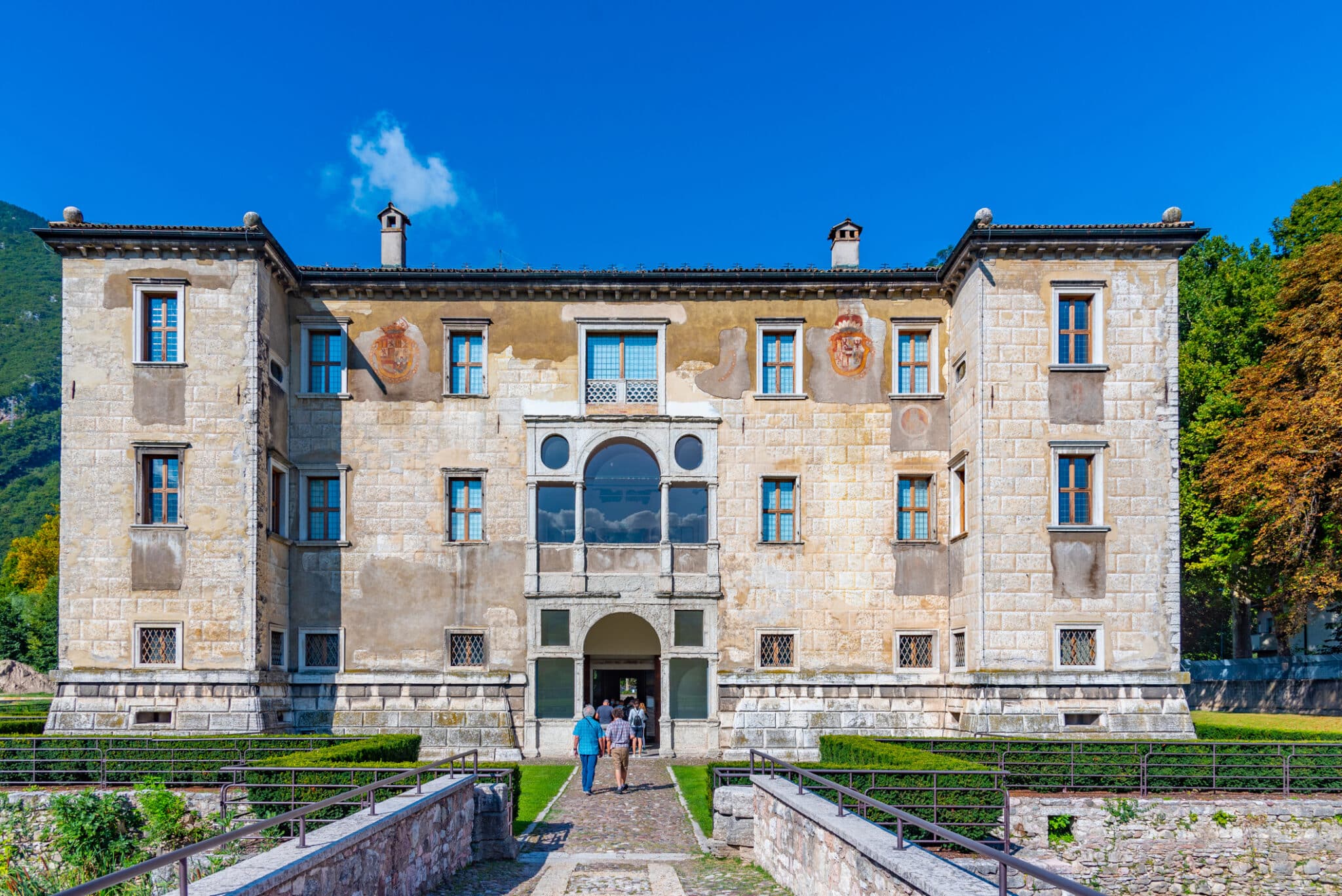 Villa storica italiana con visitatori e giardino antistante.