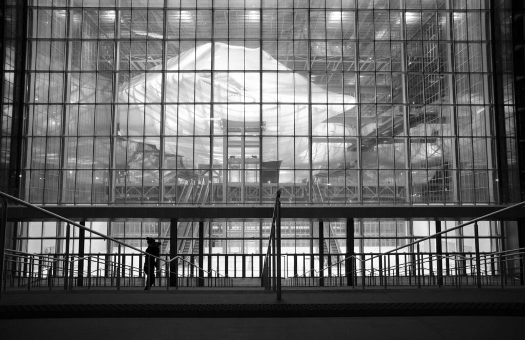 Silueta humana delante de moderna fachada de cristal en blanco y negro.