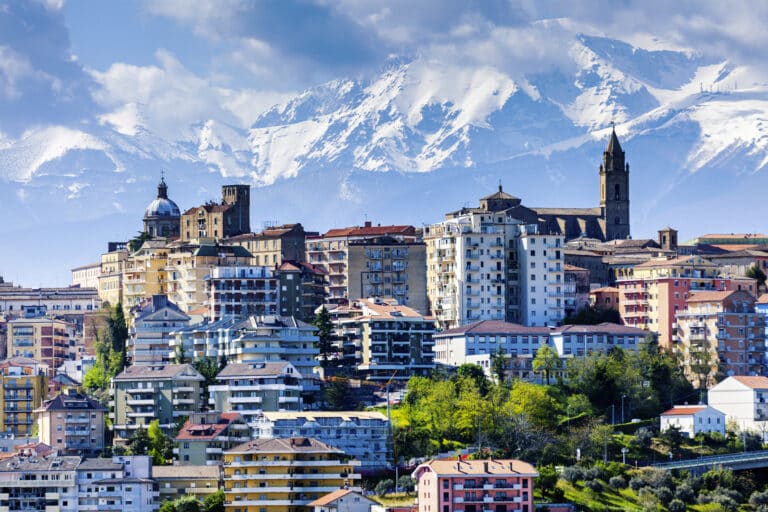 Ville italienne avec des montagnes enneigées en arrière-plan.