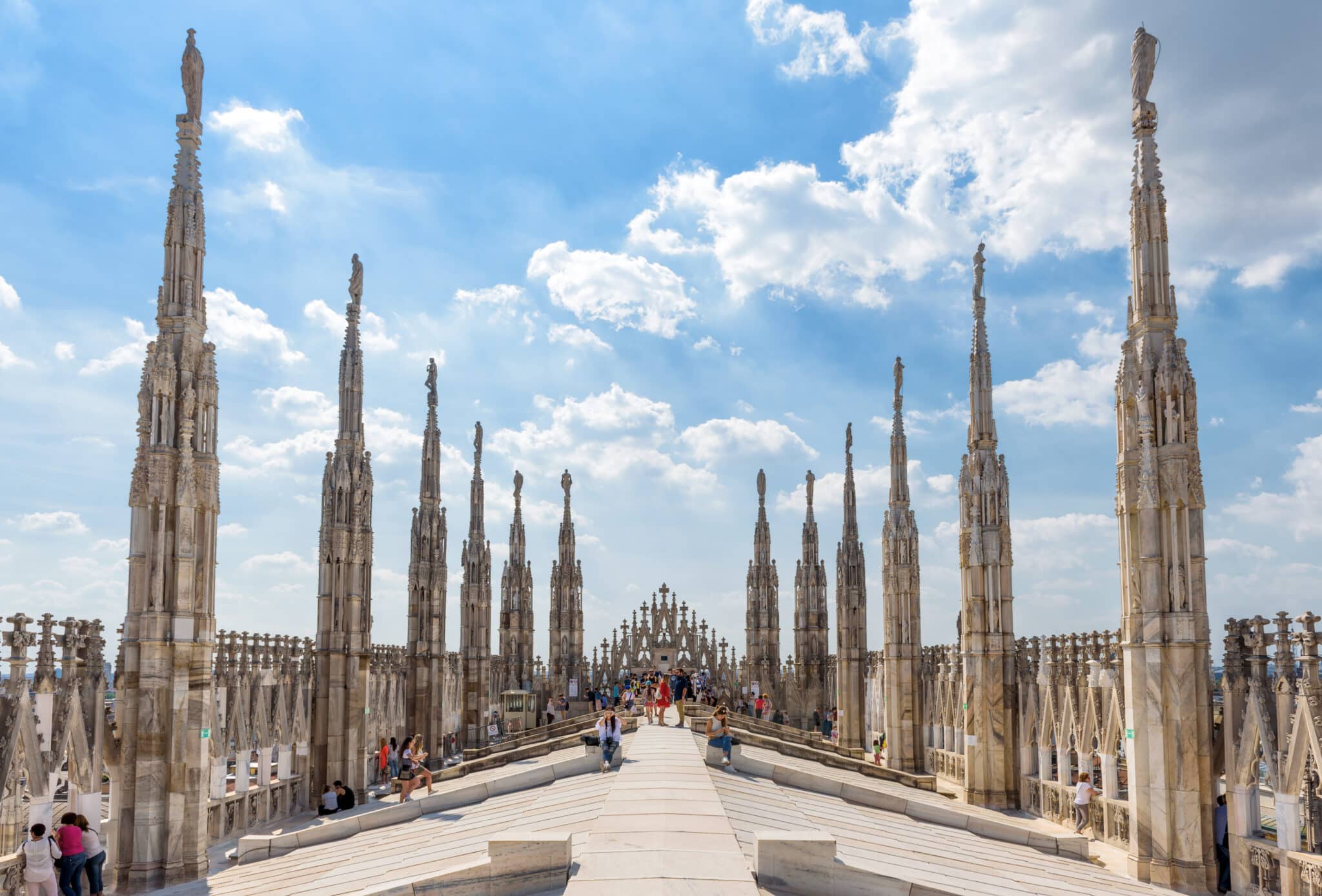 Terrazza Duomo di Milano con turisti e cielo azzurro.