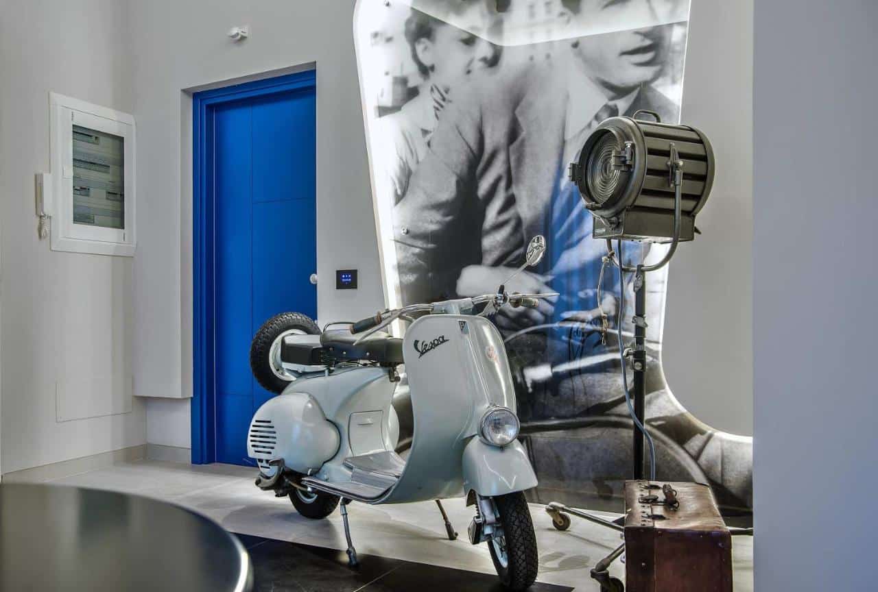 Vespa vintage in mostra con poster e faro d'epoca.