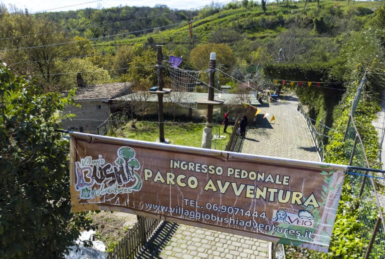 Bannière d'entrée d'un parc d'aventure et paysage verdoyant.