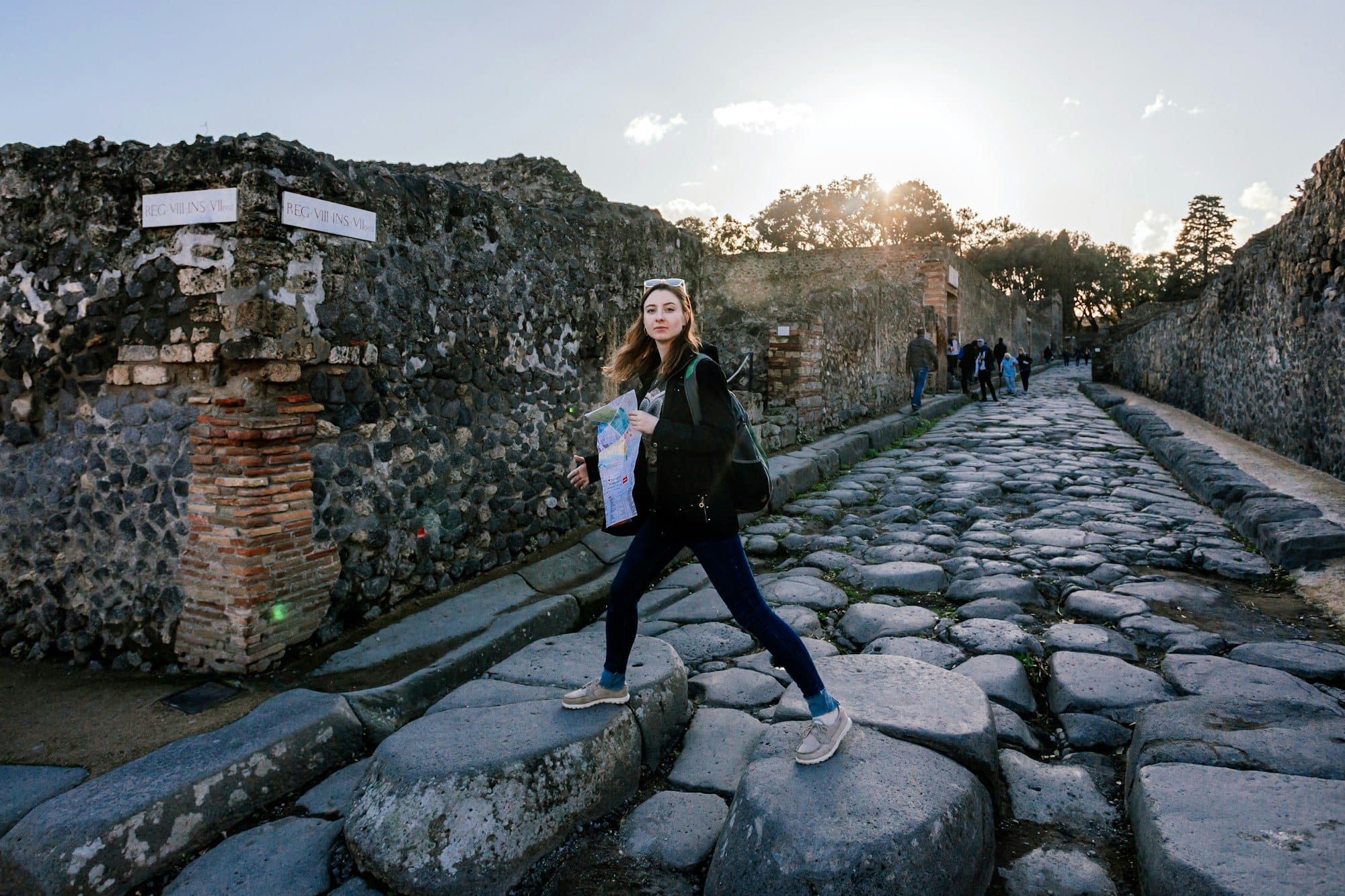 Una giovane ragazza cammina con una mappa in mano per le strade dell'antica città di Pompei.