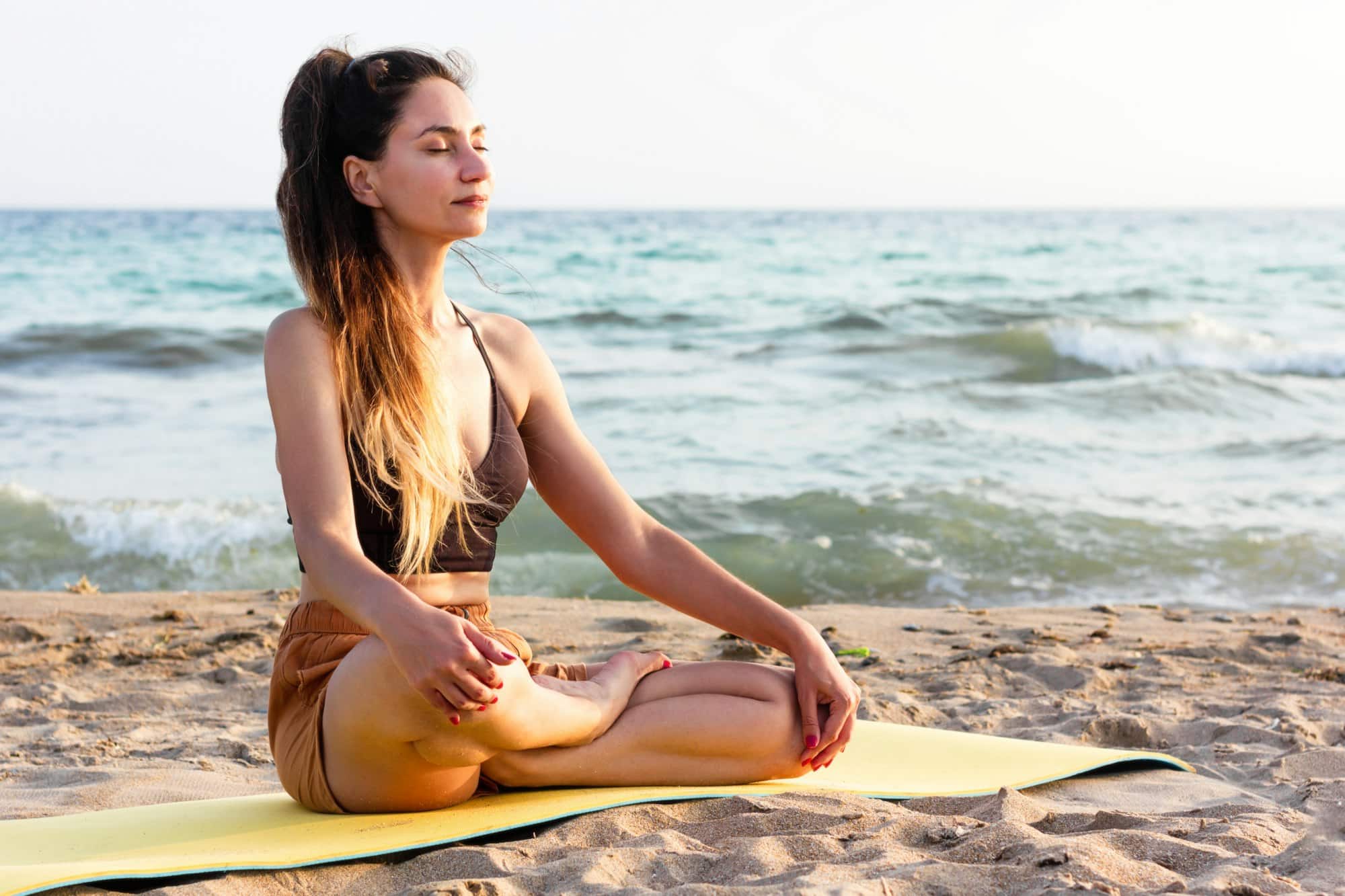 Donna che pratica yoga in spiaggia