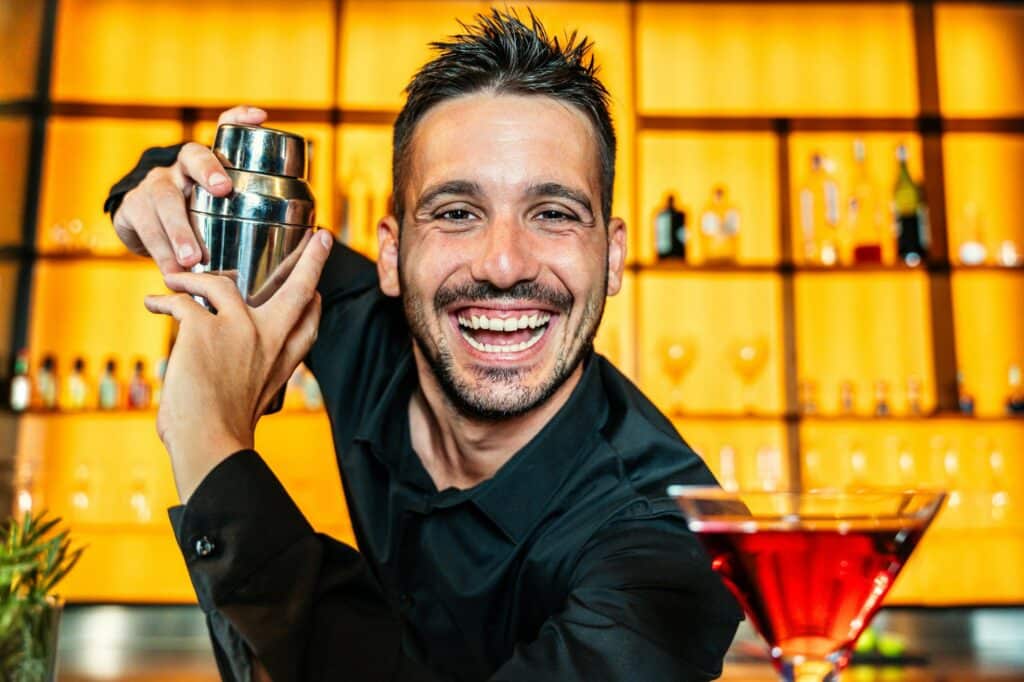 Barman guapo preparando cócteles en discoteca