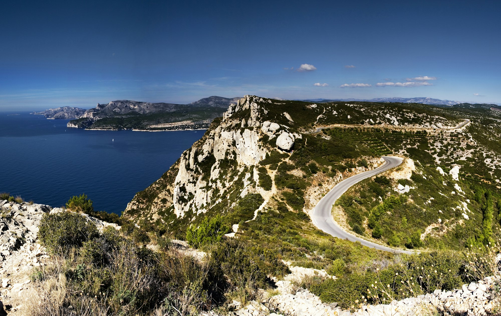 Vista dall'alto della Corniche des Crêtes circondata da vegetazione e dal mare in Francia.