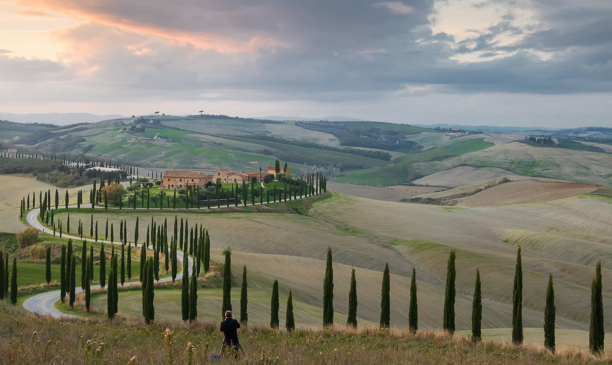 Il fotografo scatta una foto di una fattoria e di una strada con cipressi al tramonto in Val d'Orcia. Toscana. Italia