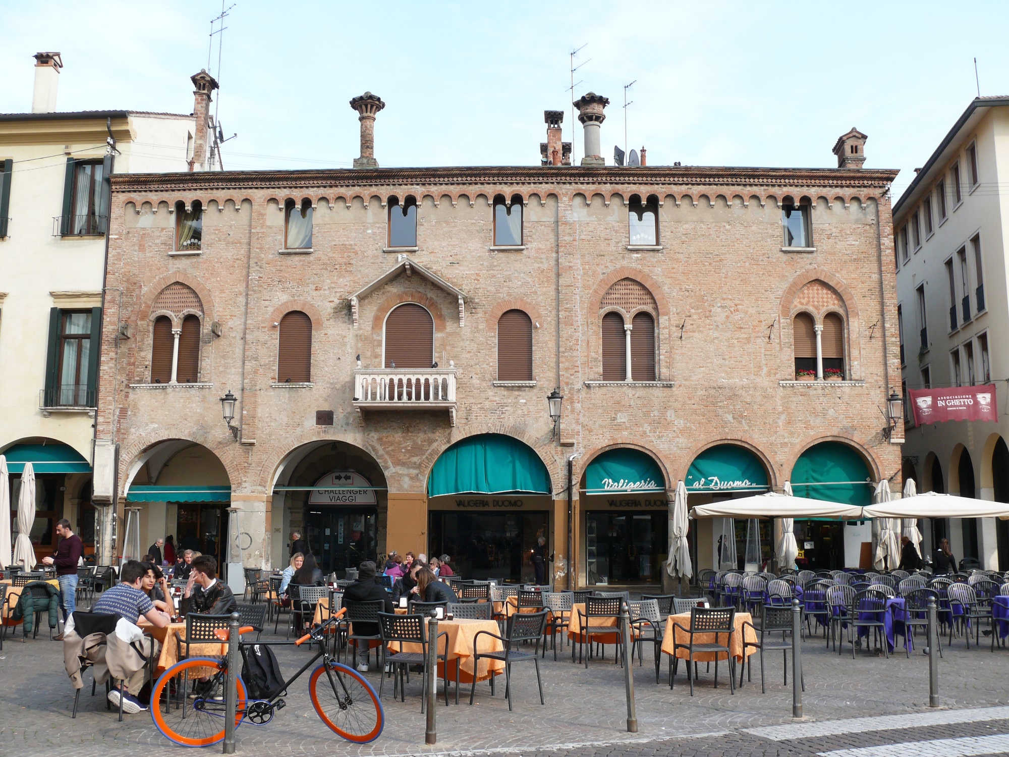 Piazza italiana con caffè all'aperto e architettura storica.