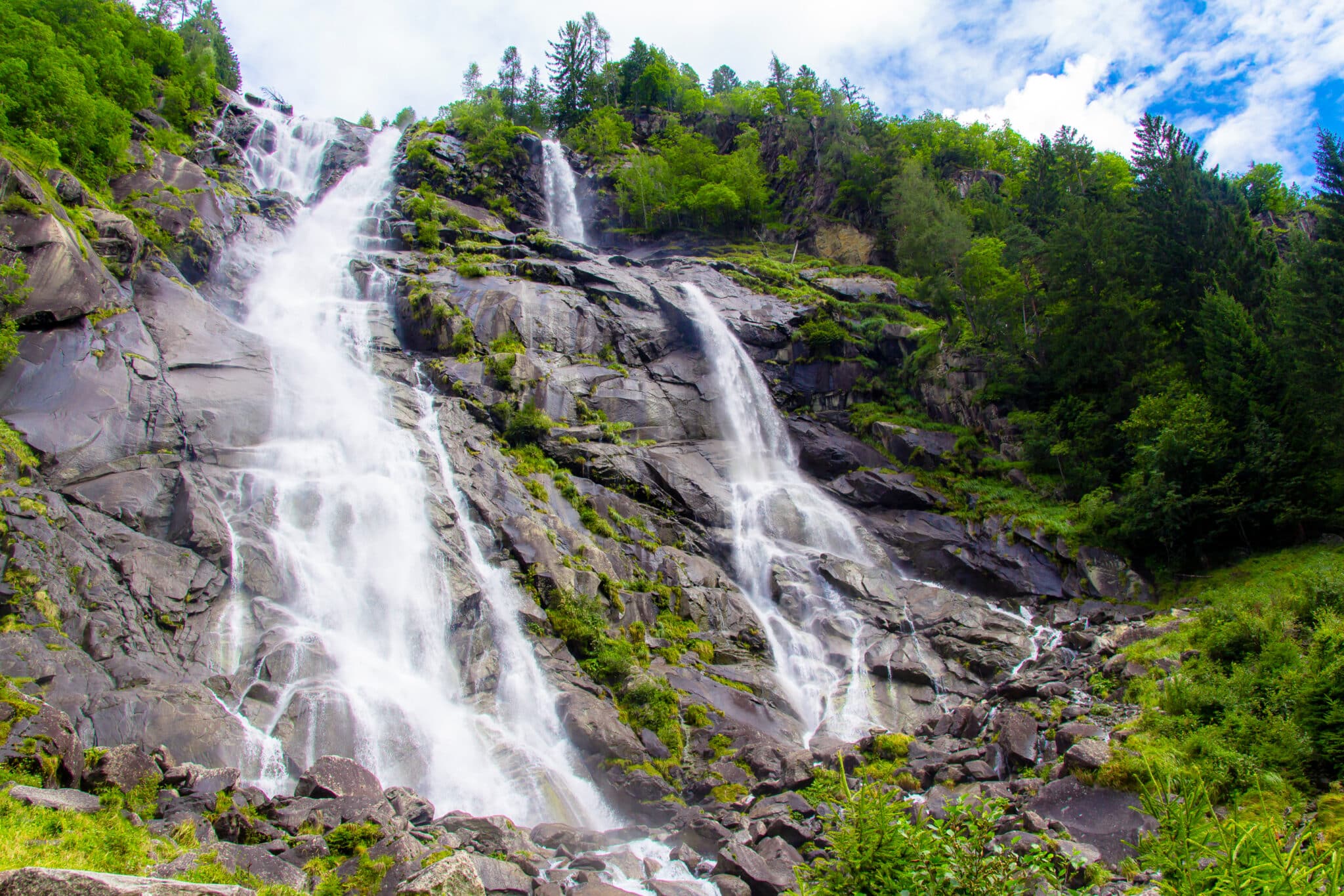 Cascata montana tra alberi verdi.