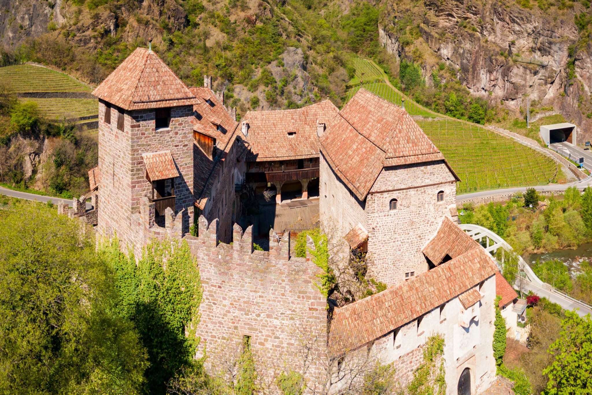 Castello medievale tra colline verdi e vigneti.