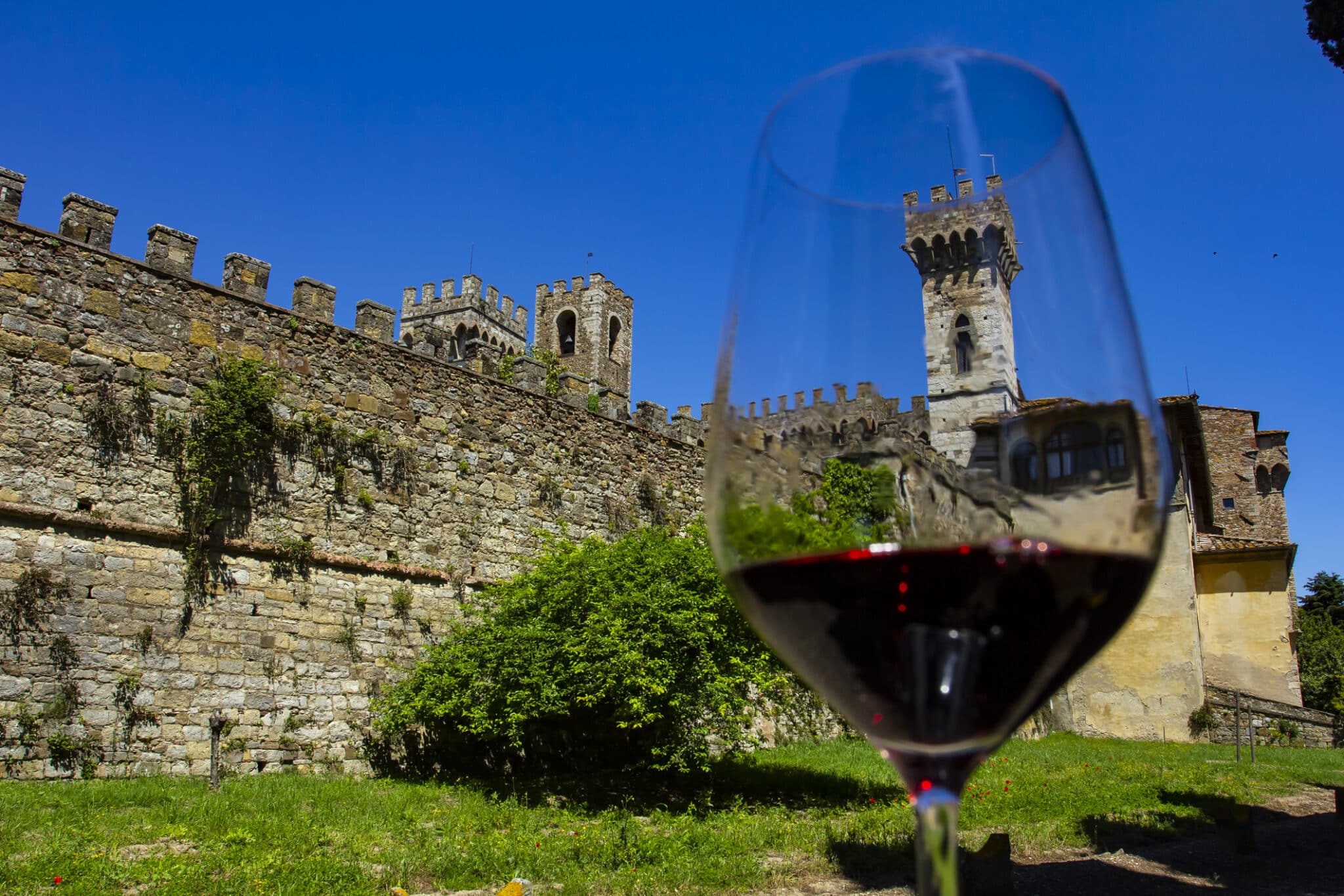 Castello italiano con bicchiere di vino in primo piano.