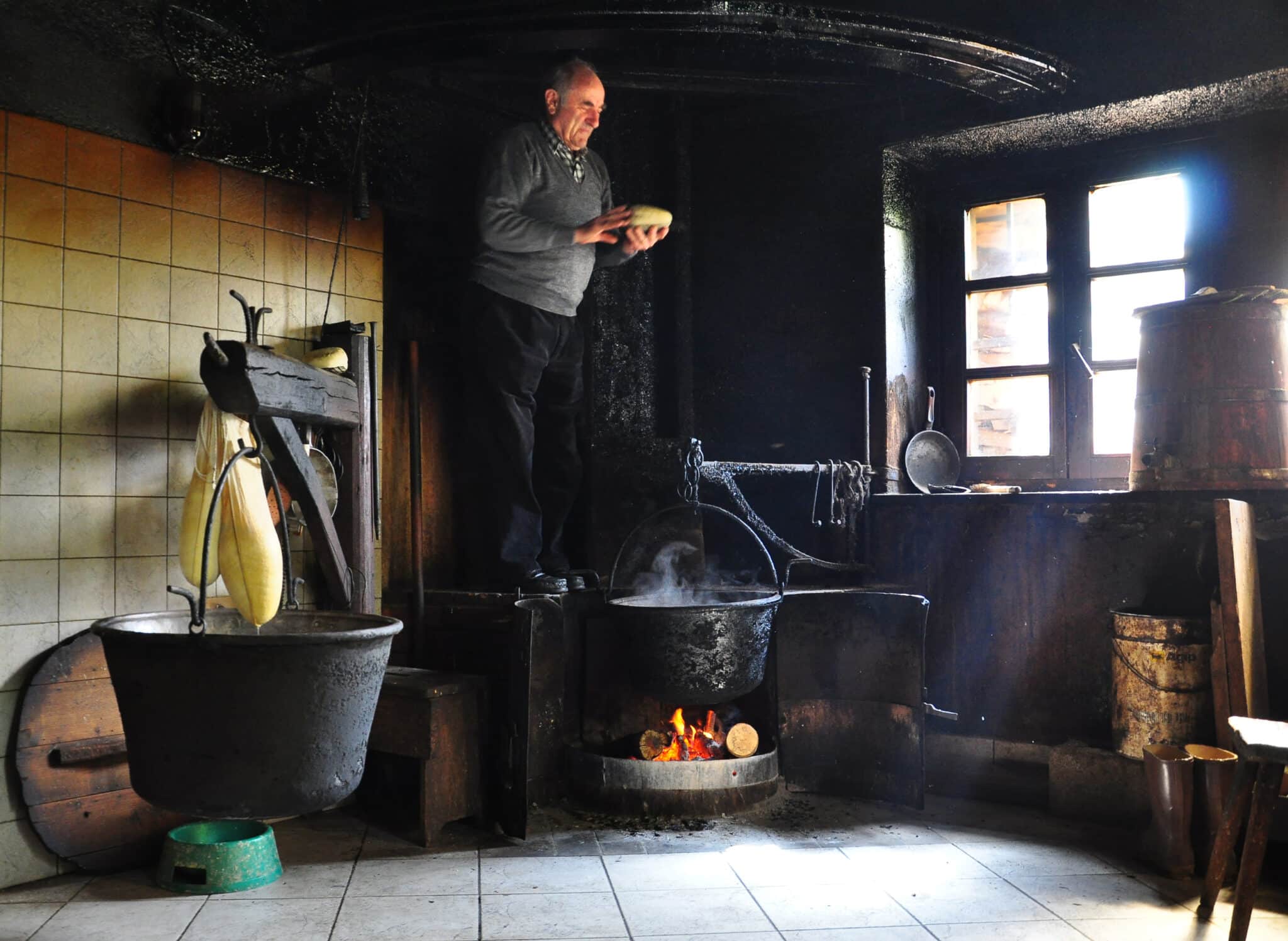 Uomo nella cucina tradizionale con fuoco.