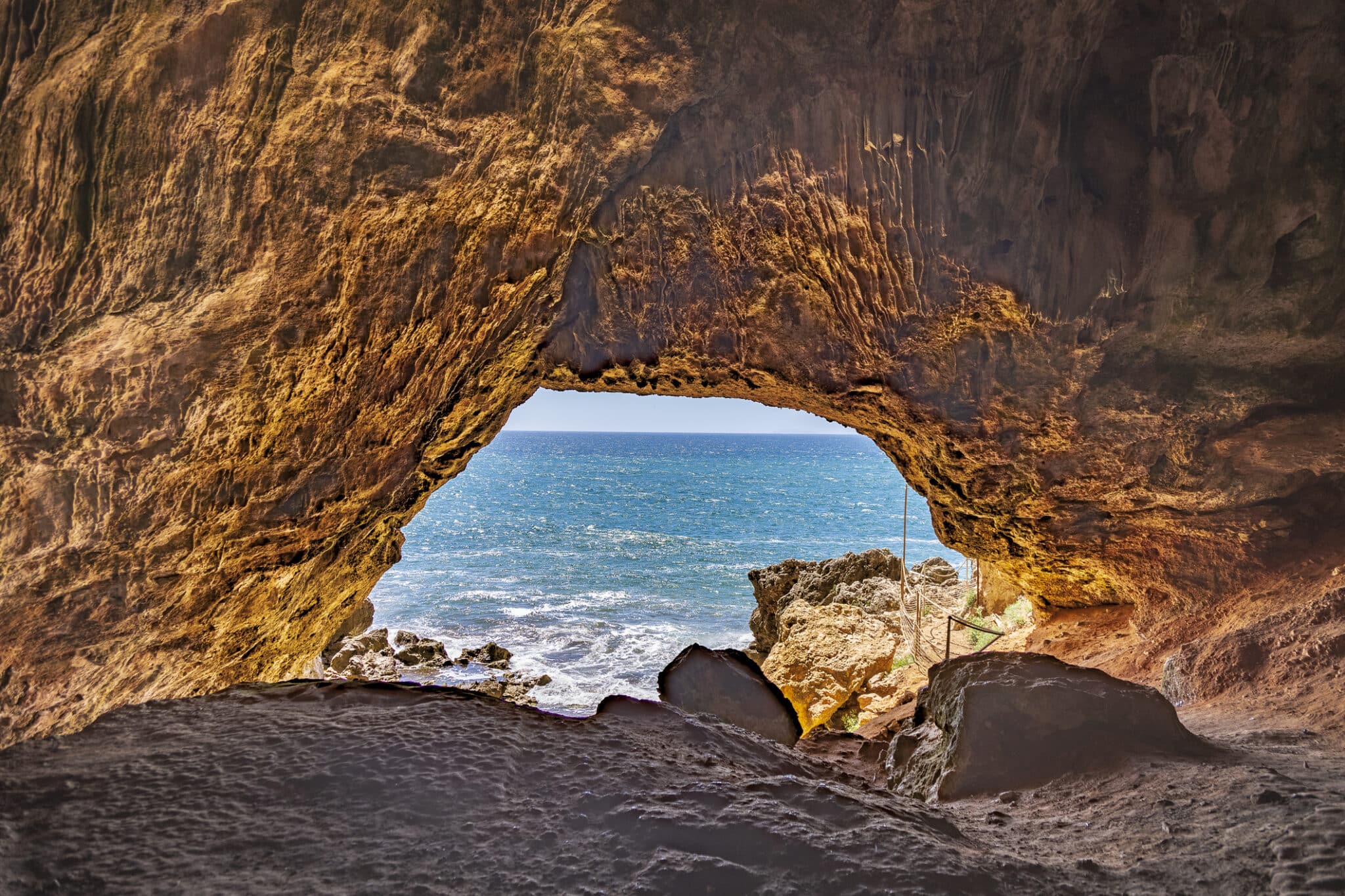 Grotta sul mare con vista cielo azzurro.