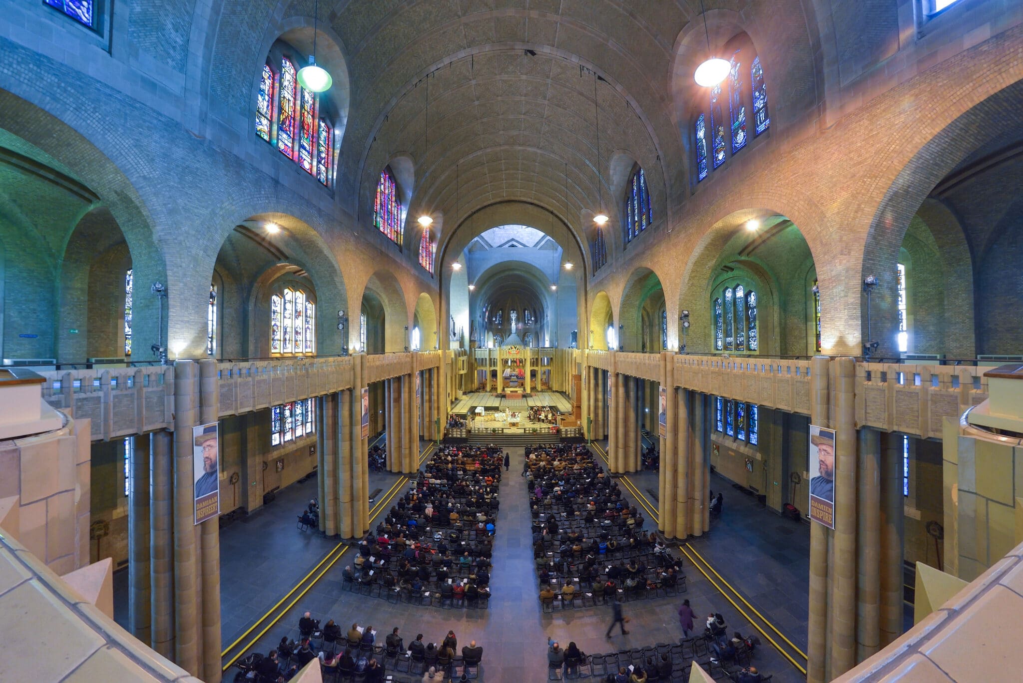 Gothic church interior, stained glass windows, seated worshippers.