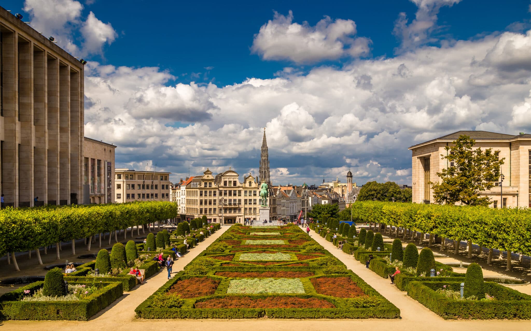 Formal garden with city view and cloudy sky.