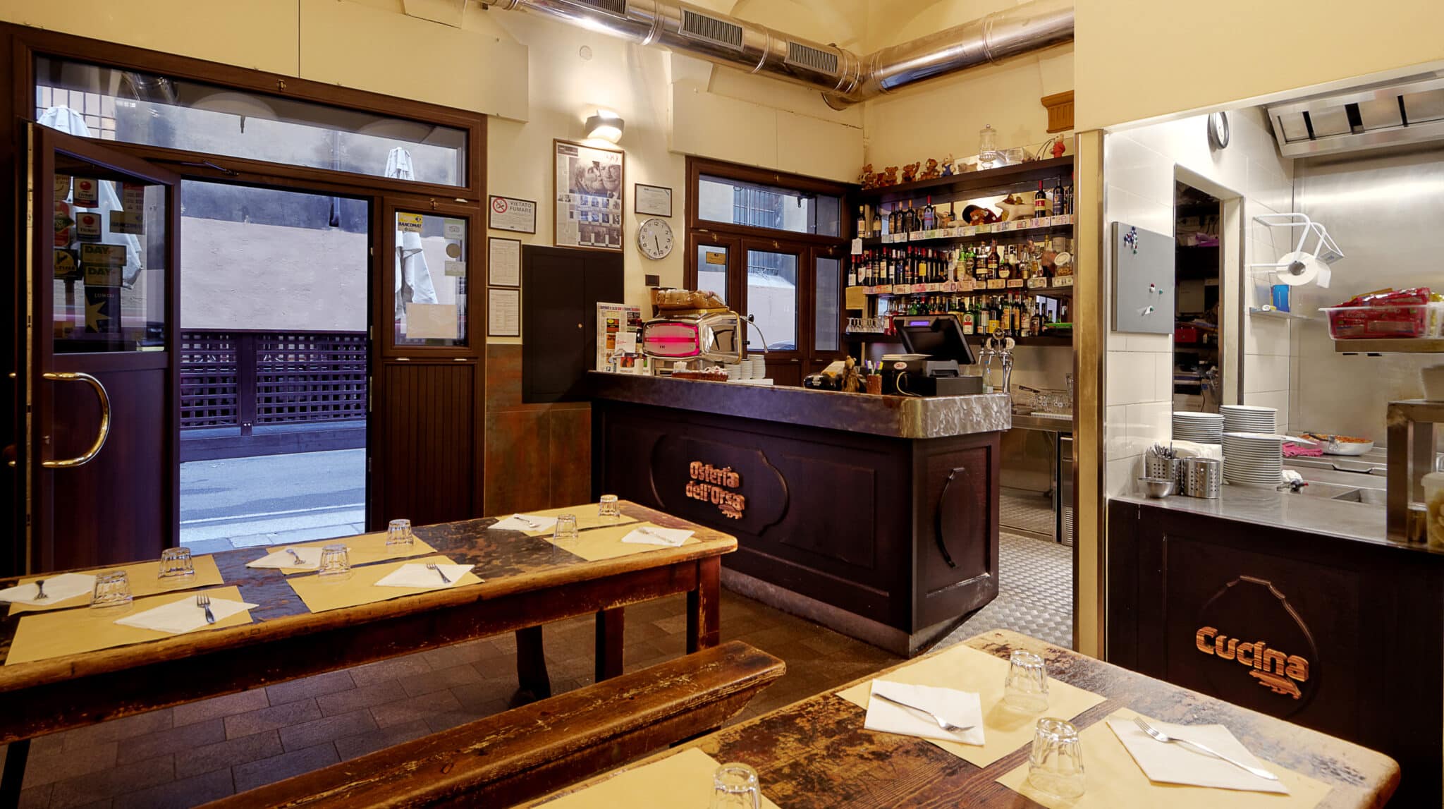 Interno tradizionale osteria italiana con tavoli apparecchiati.