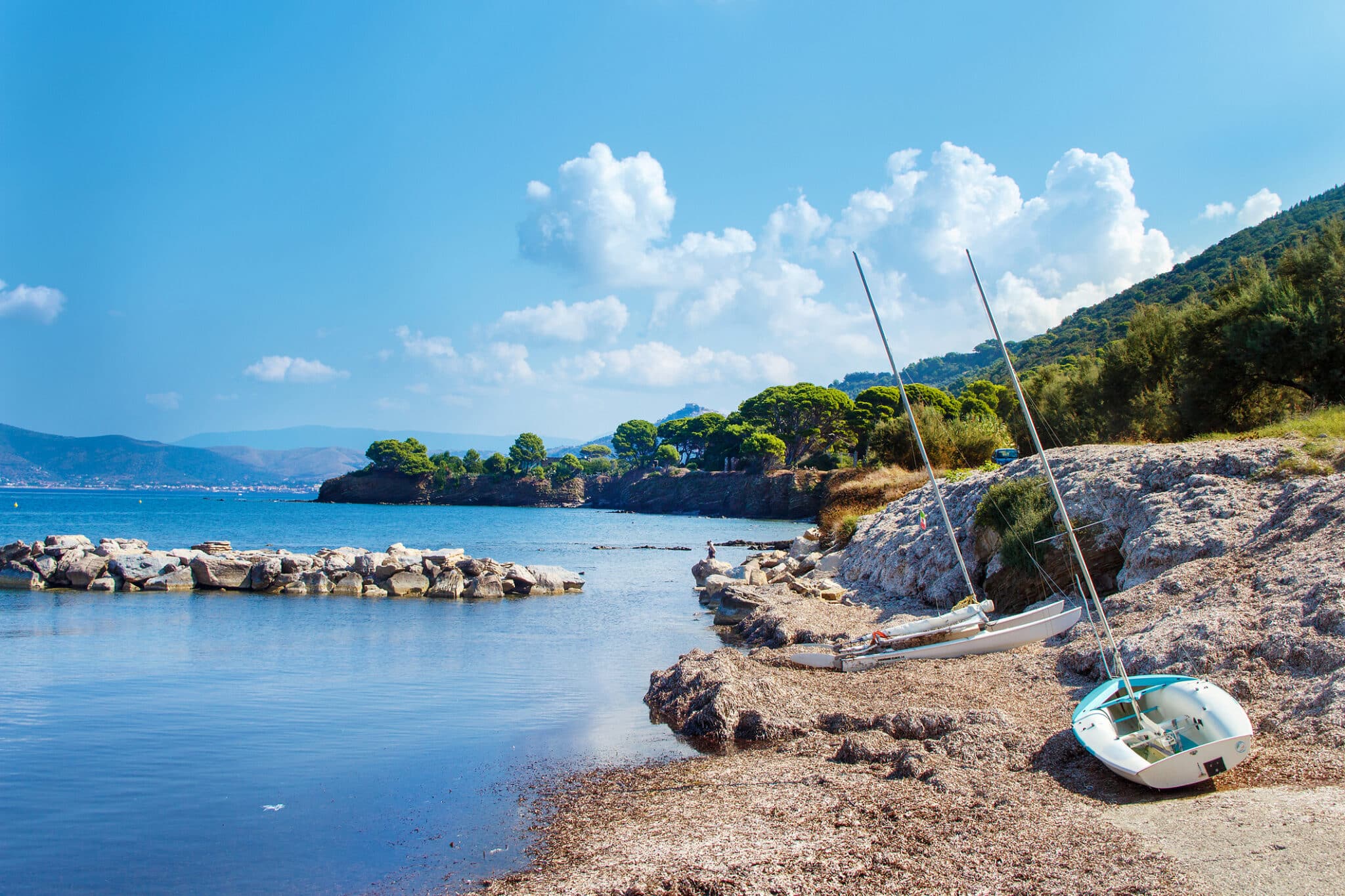 Spiaggia con barche a vela e mare cristallino.