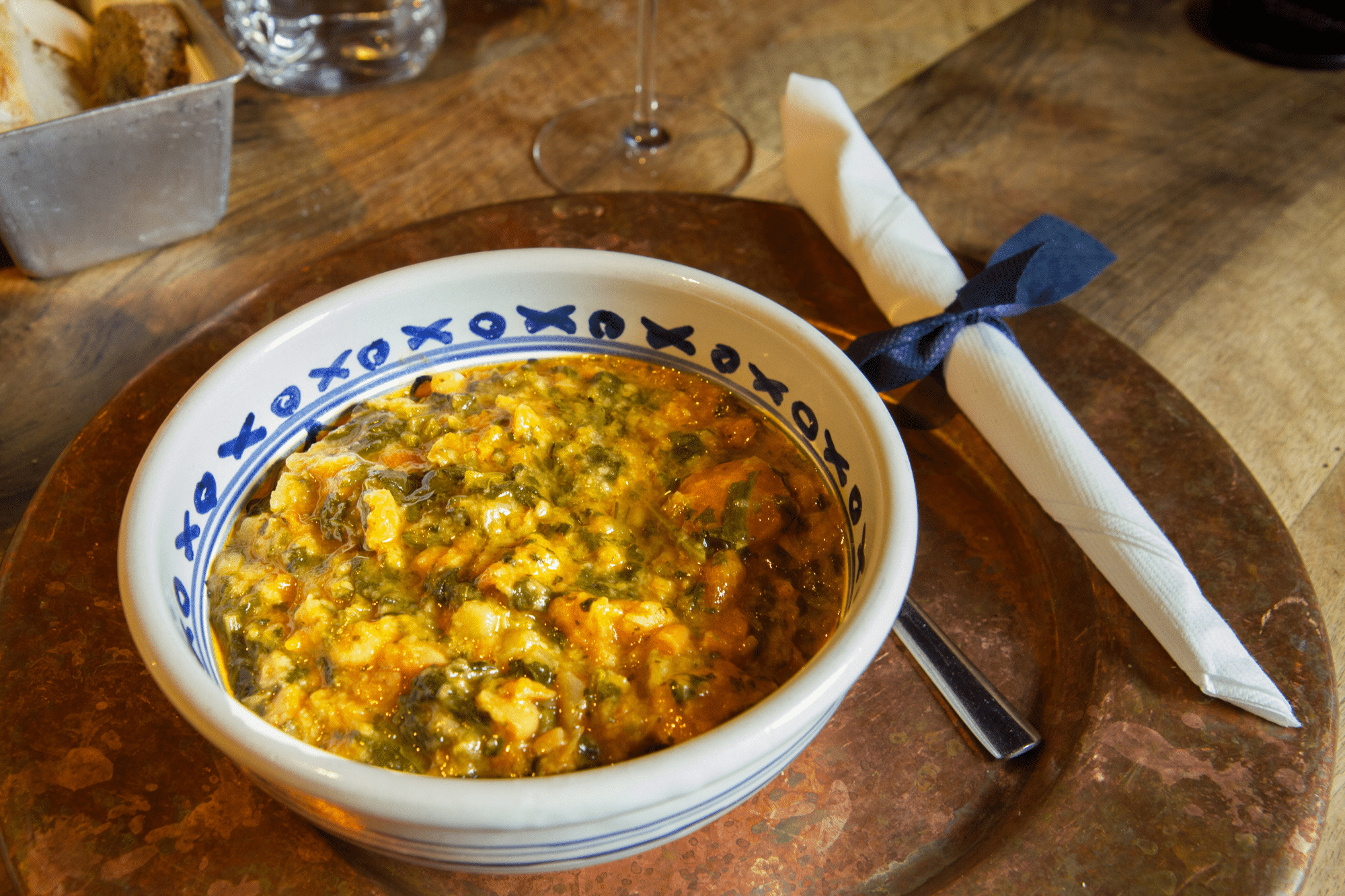 Ciotola decorata con Ribollita Toscana accanto a pane rustico e un tovagliolo.