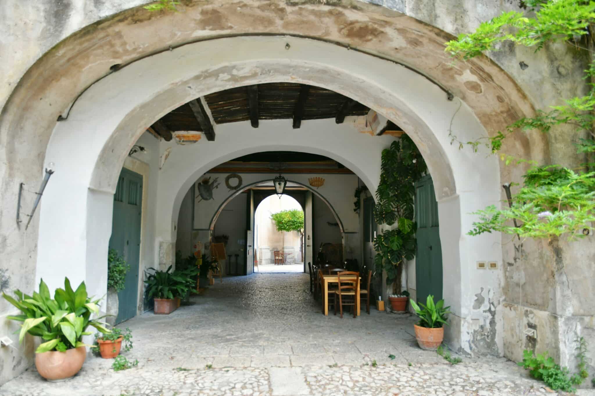 Porche rustique avec plantes et mobilier d'extérieur.