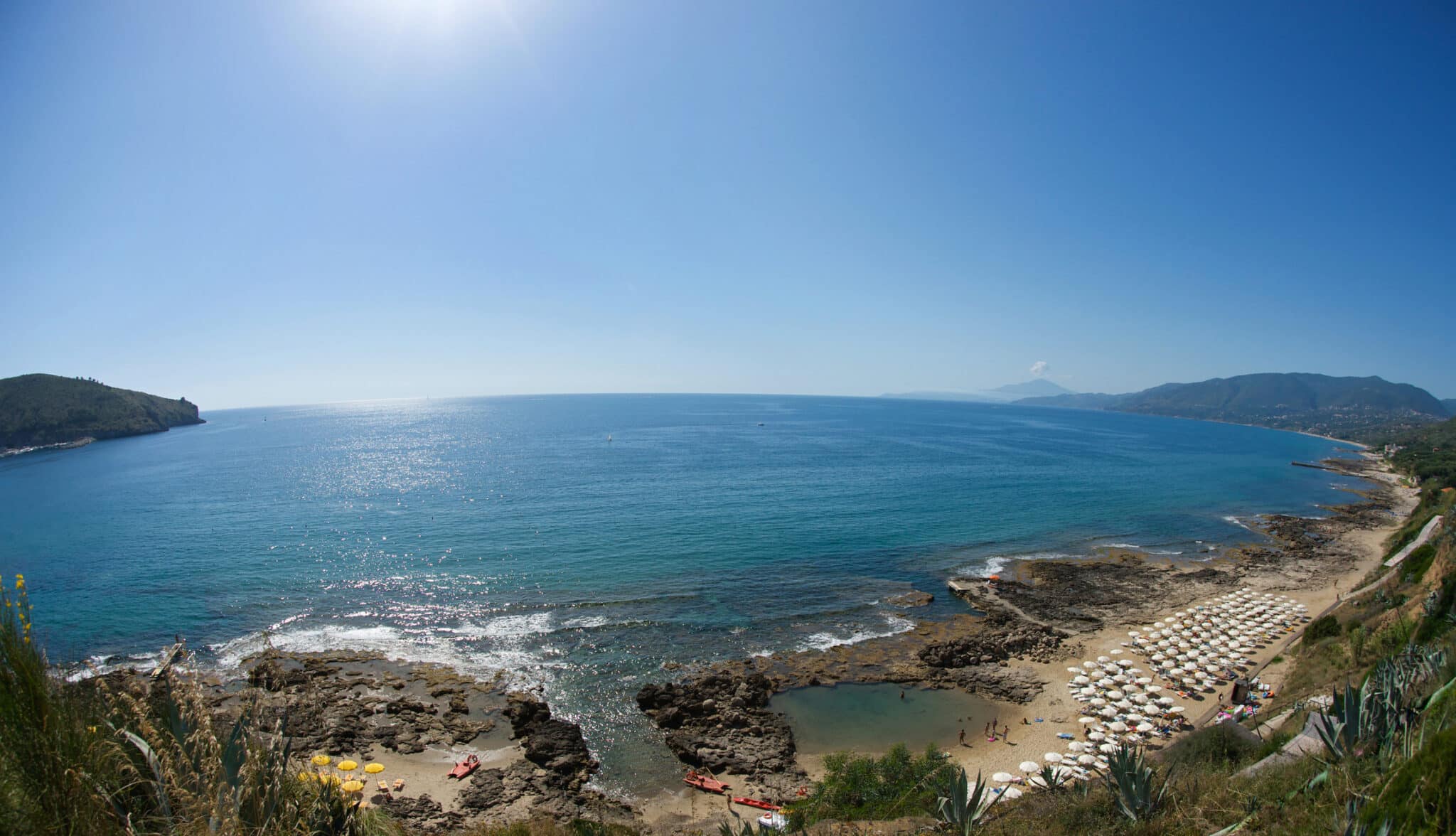 Panorama costiero italiano con spiaggia e mare blu.