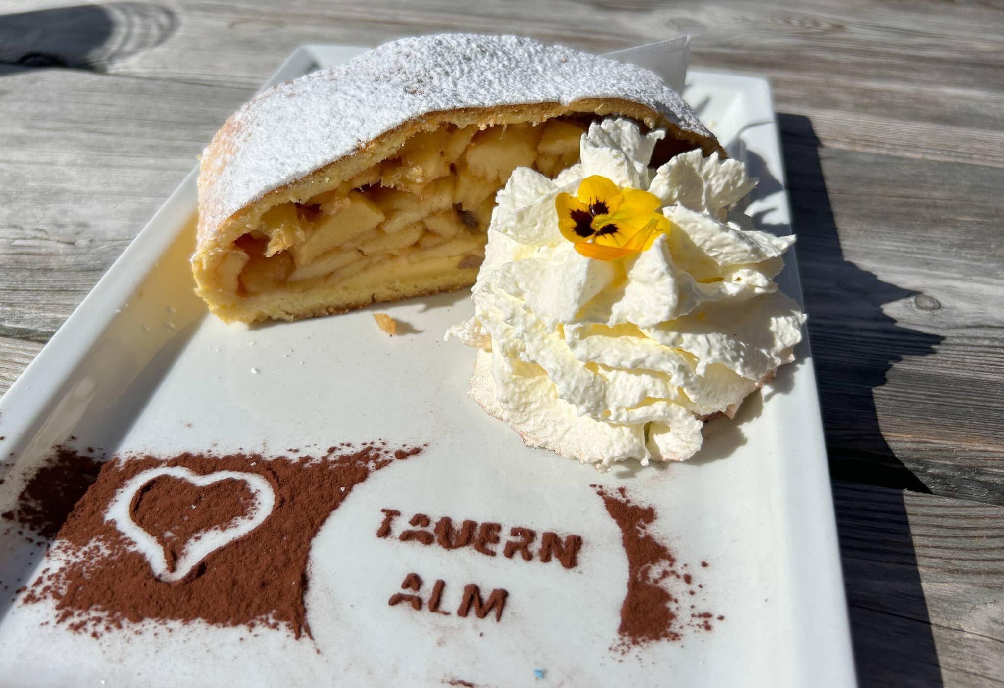 Strudel di mele con panna e decorazione di cacao.