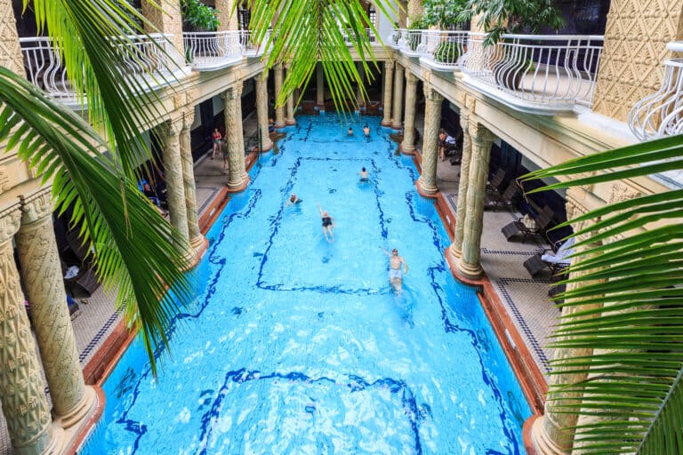 Piscina interna di lusso con colonne e persone.