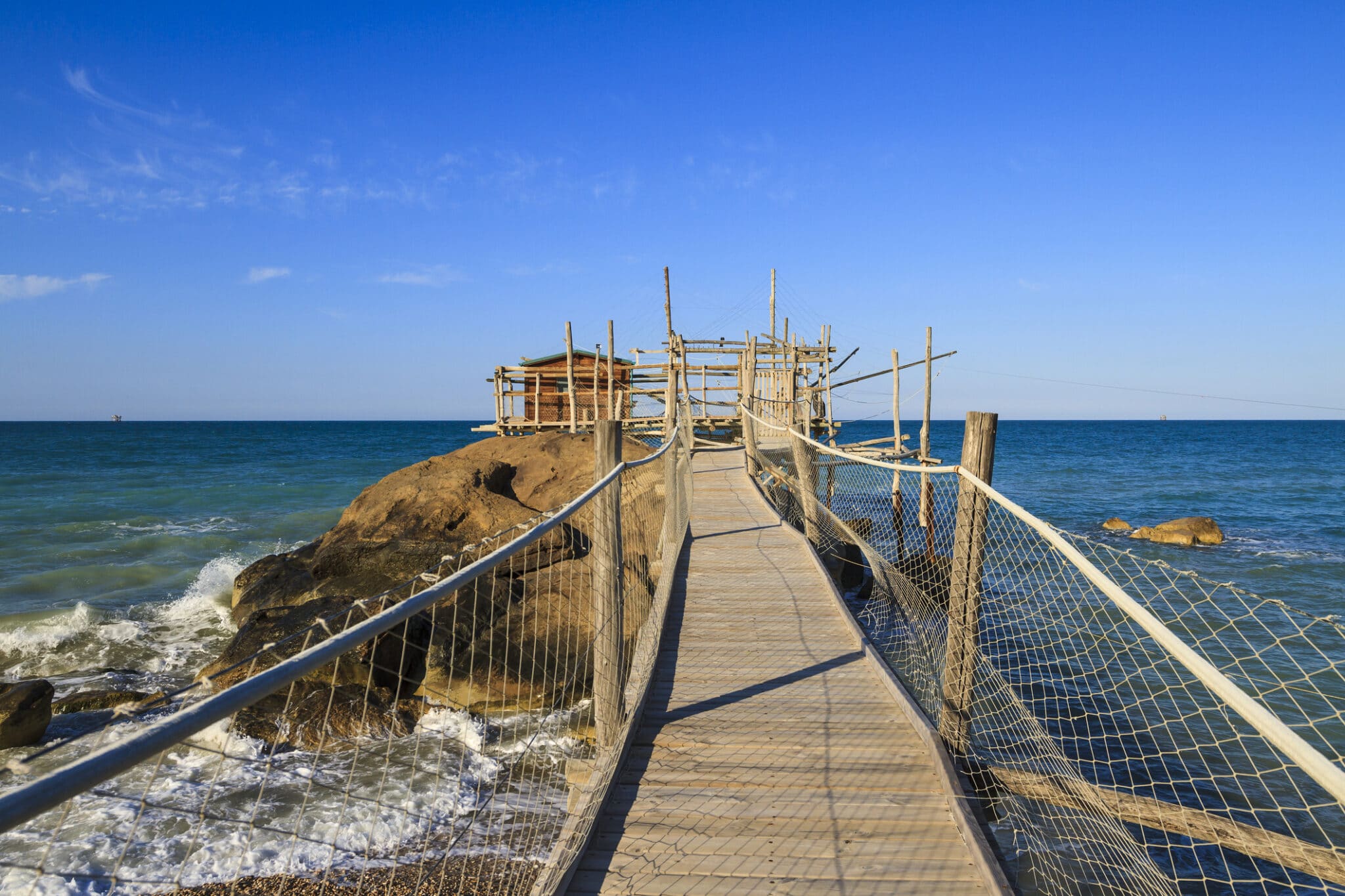 Ponte di legno verso casa sull'acqua, mare, cielo azzurro.