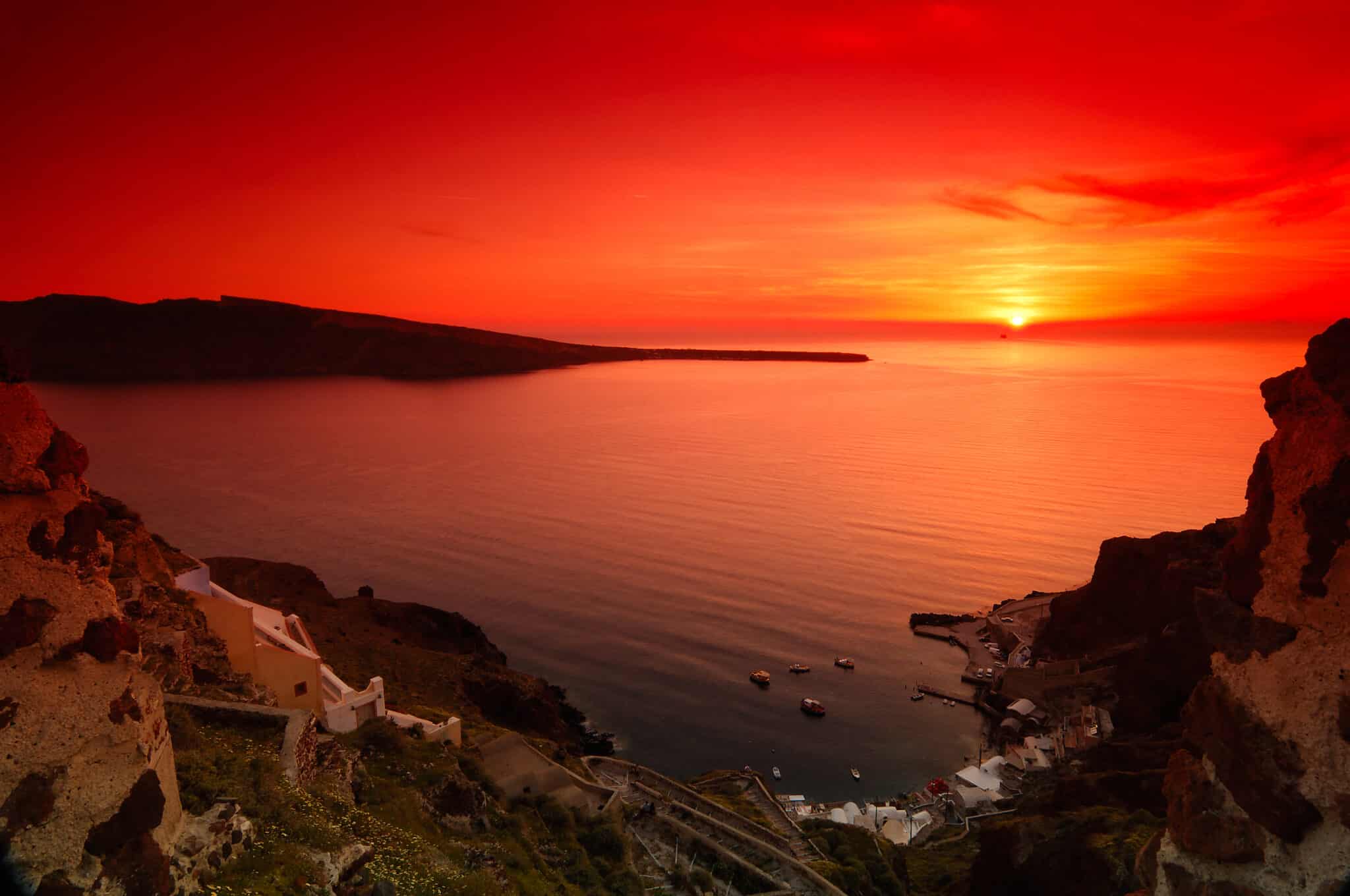 Tramonto arancione sul mare con paesino costiero.