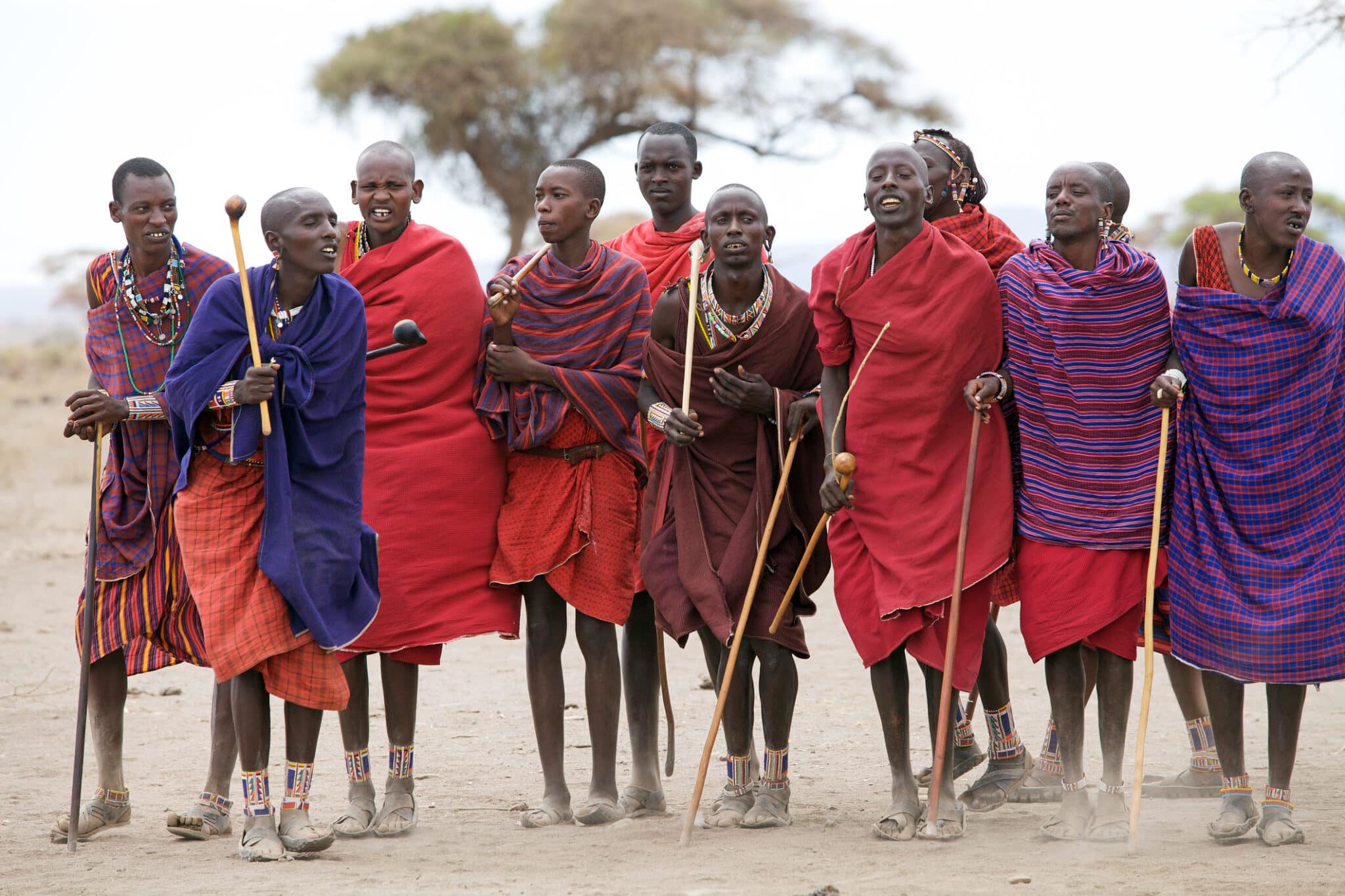 Uomini del Masai con il vestito, la collana e gli orecchini tradizionali fuori del villaggio