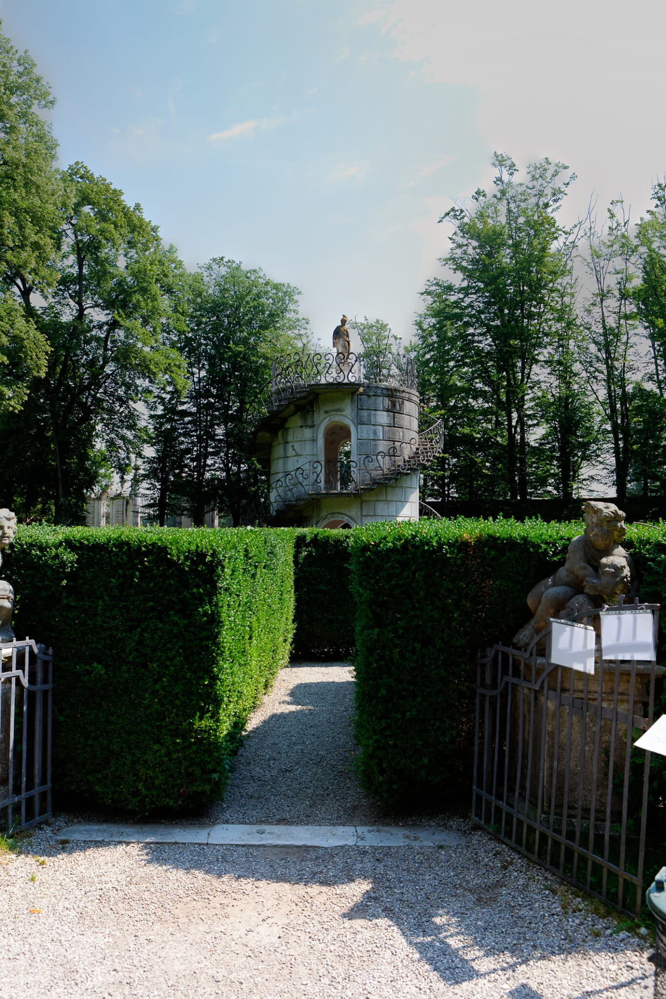 Giardino formale con pergolato e siepi verdi.