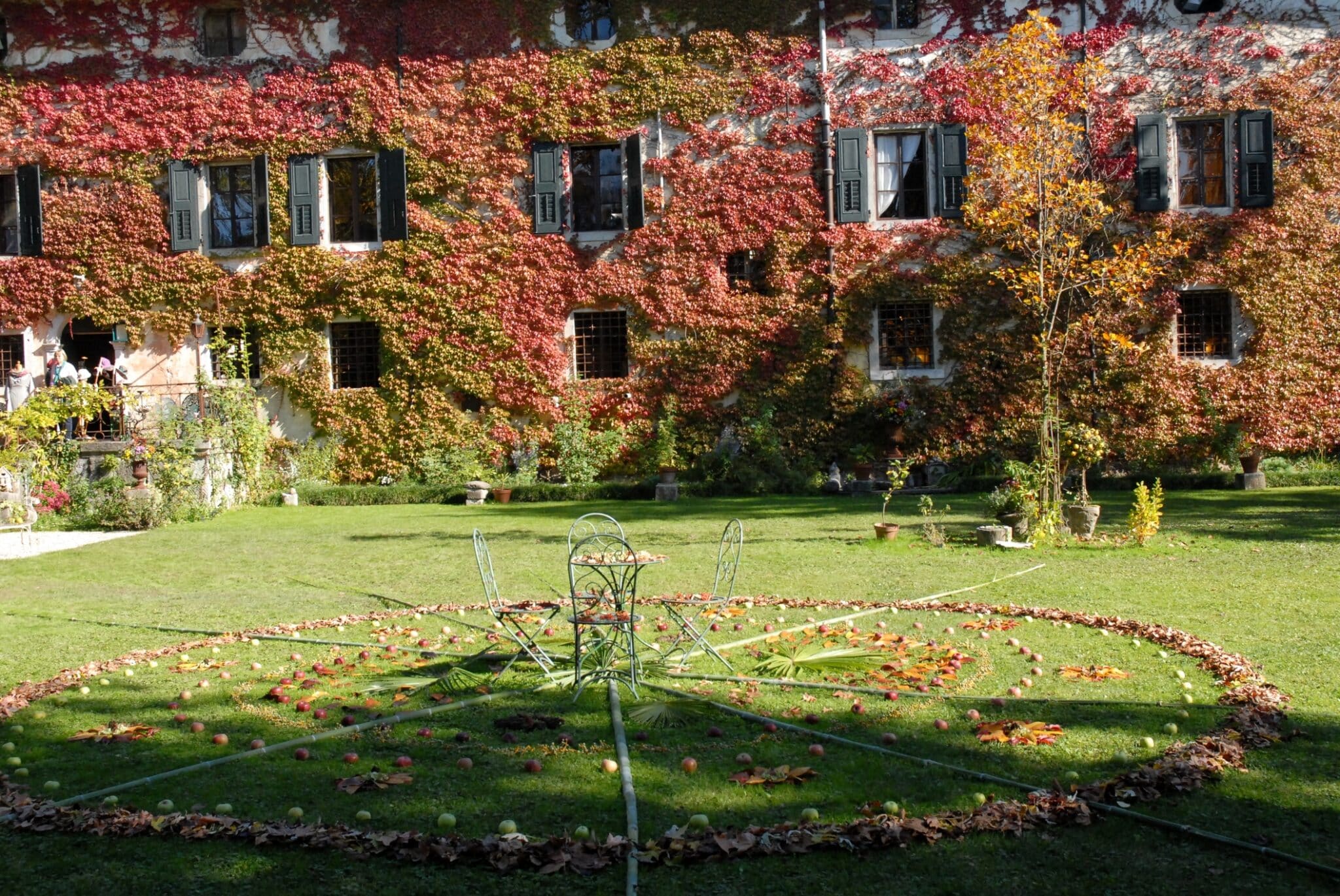 Cerchio di foglie con mele e tavolino nel giardino del castello nel borgo di Strassoldo Friuli (Italia).