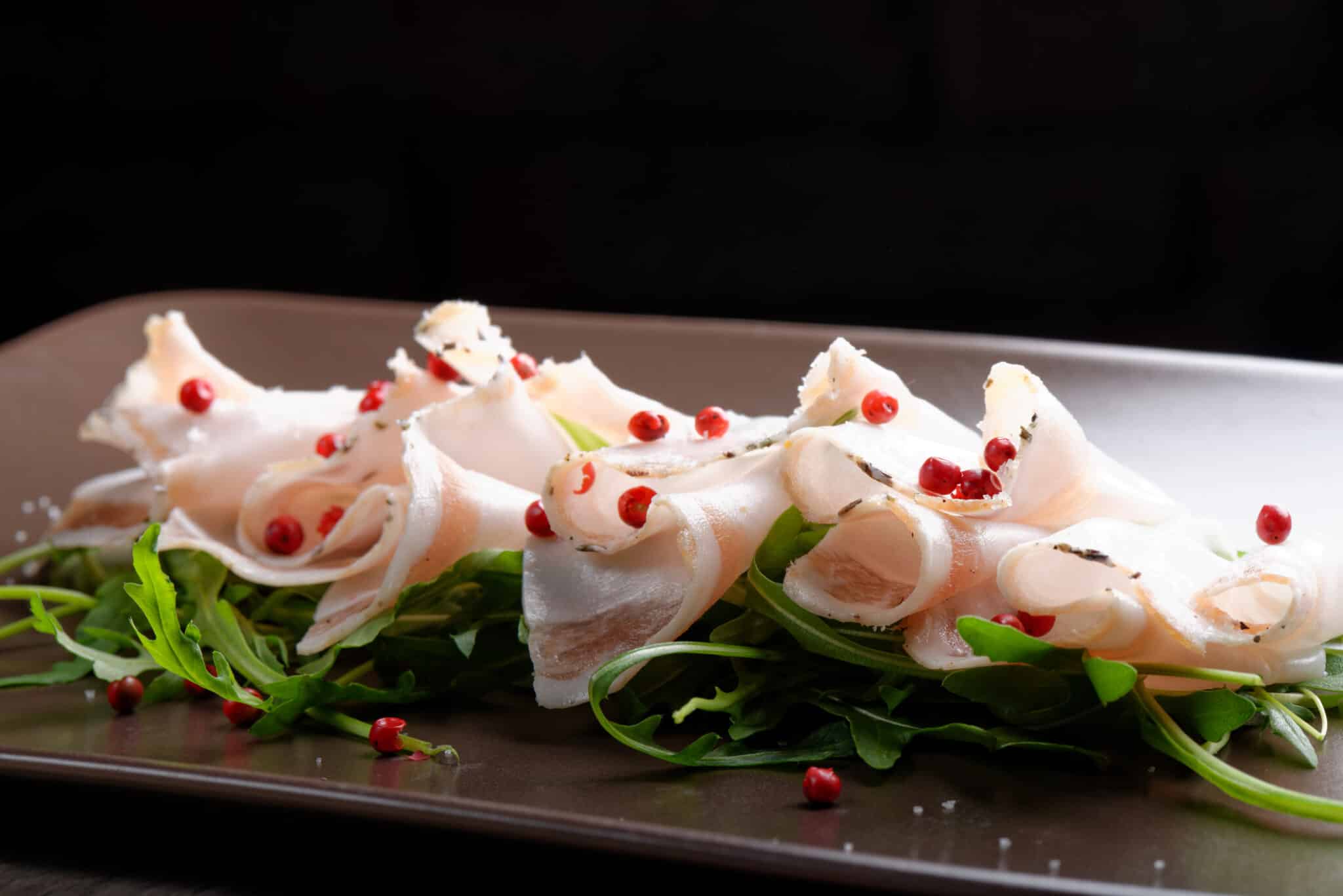 Fette di pancetta Lardo di colonnata con peperoncino e insalata per aperitivo