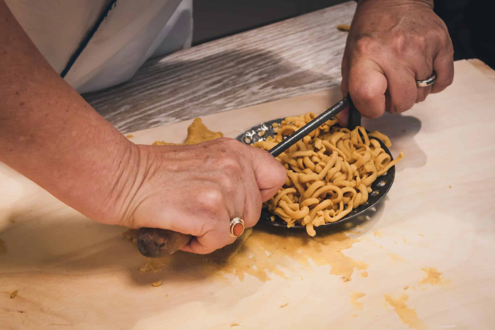 Preparazione dei passatelli di pasta fresca utilizzando l'antico attrezzo della tradizione