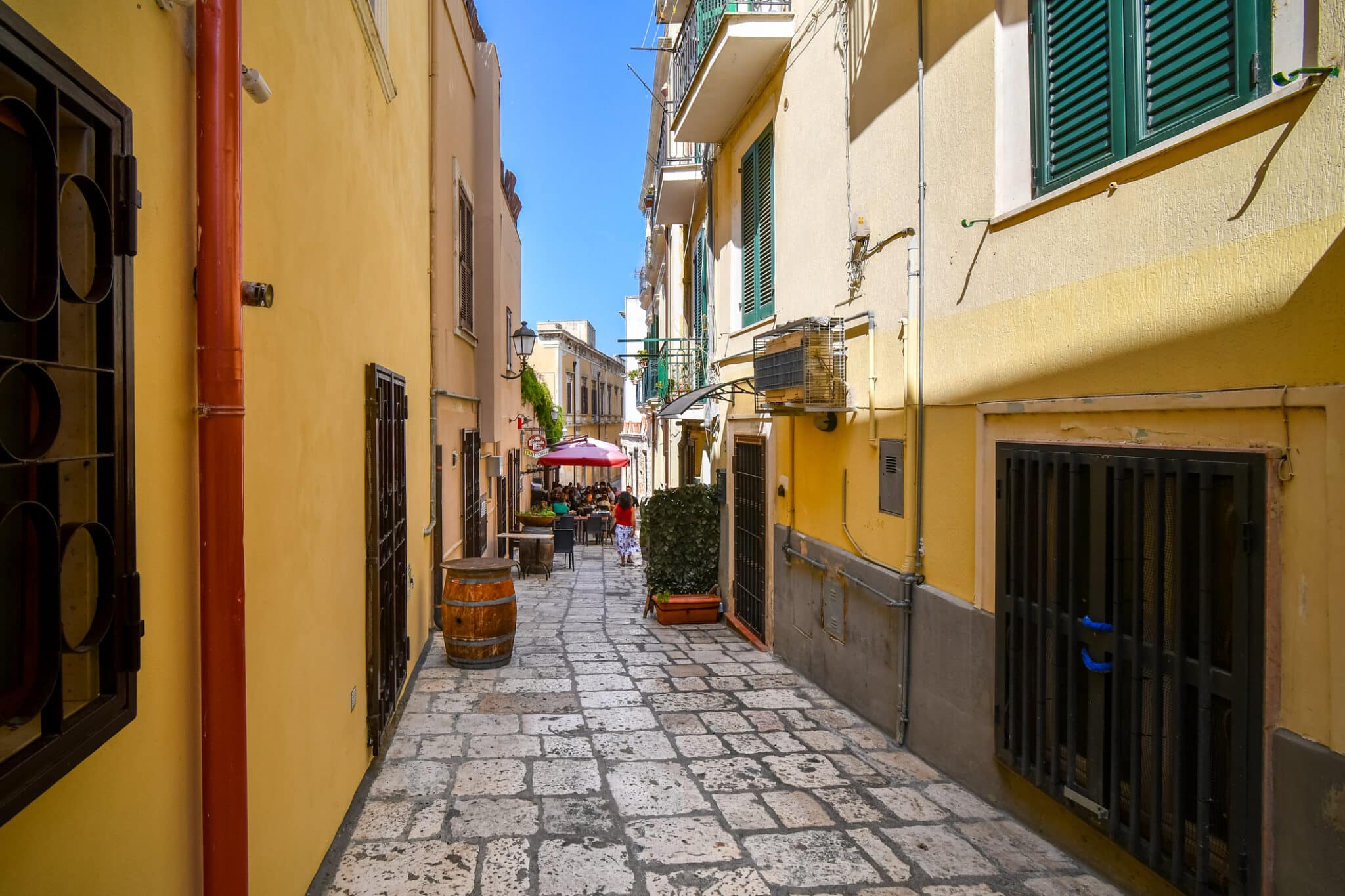 Una donna cammina lungo uno stretto vicolo colorato verso un bar nella città italiana di Brindisi, in Puglia.