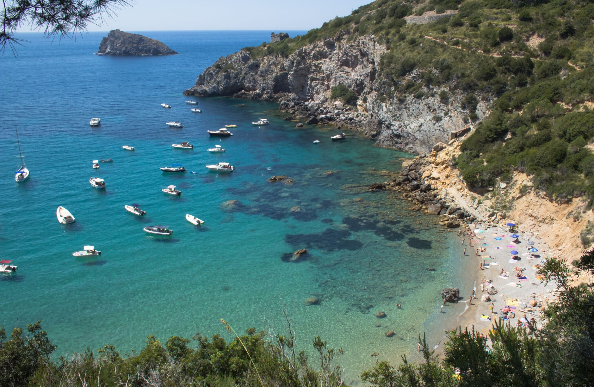 Spiaggia italiana con barche e acqua cristallina.