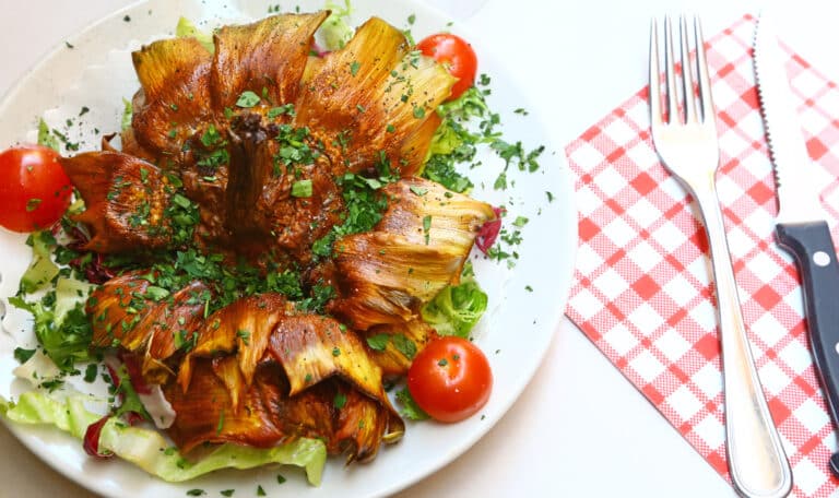 Alcachofas fritas con verduras y tomates cherry.