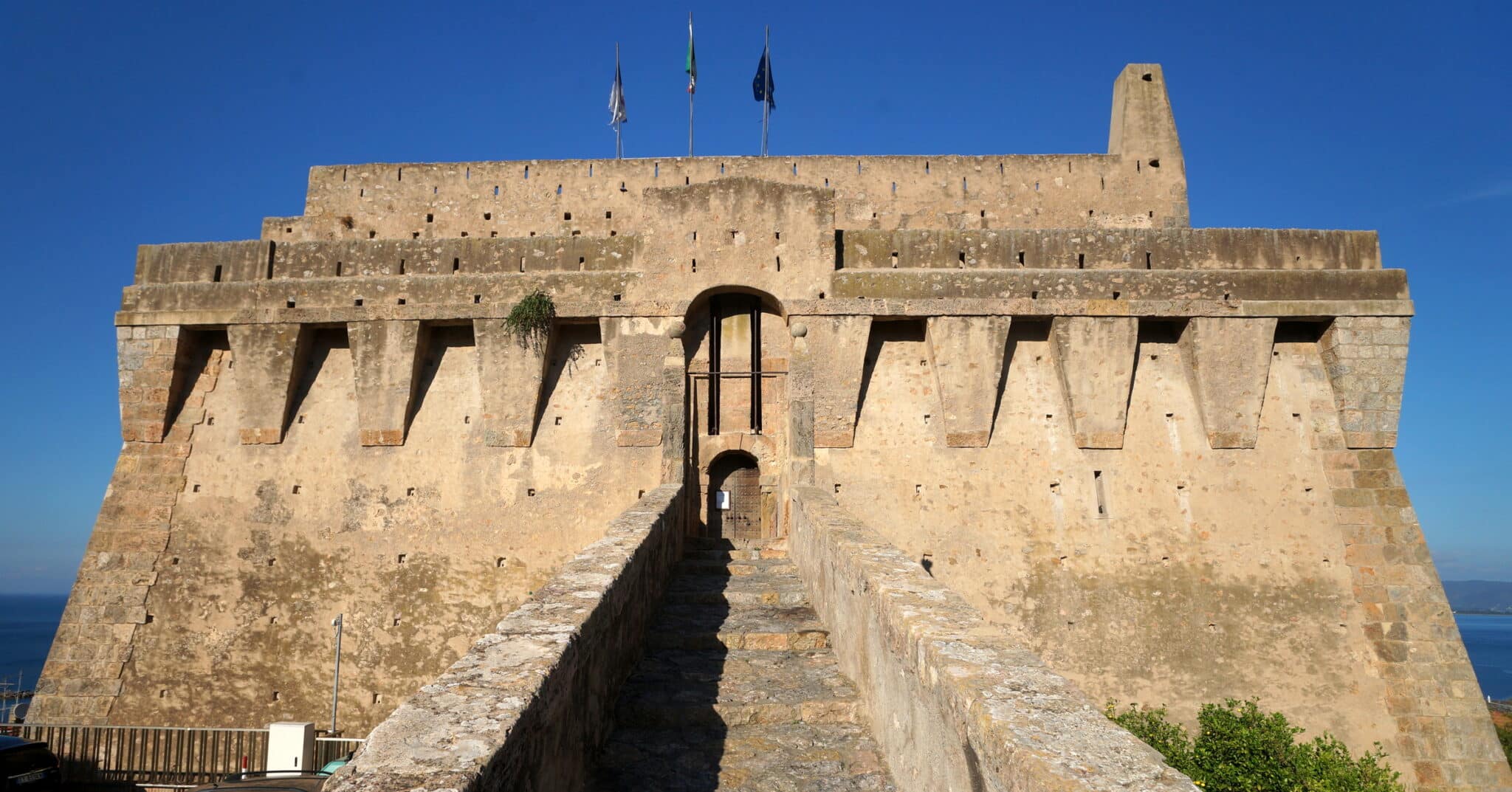 Ancienne forteresse avec drapeaux, vue de l'entrée.