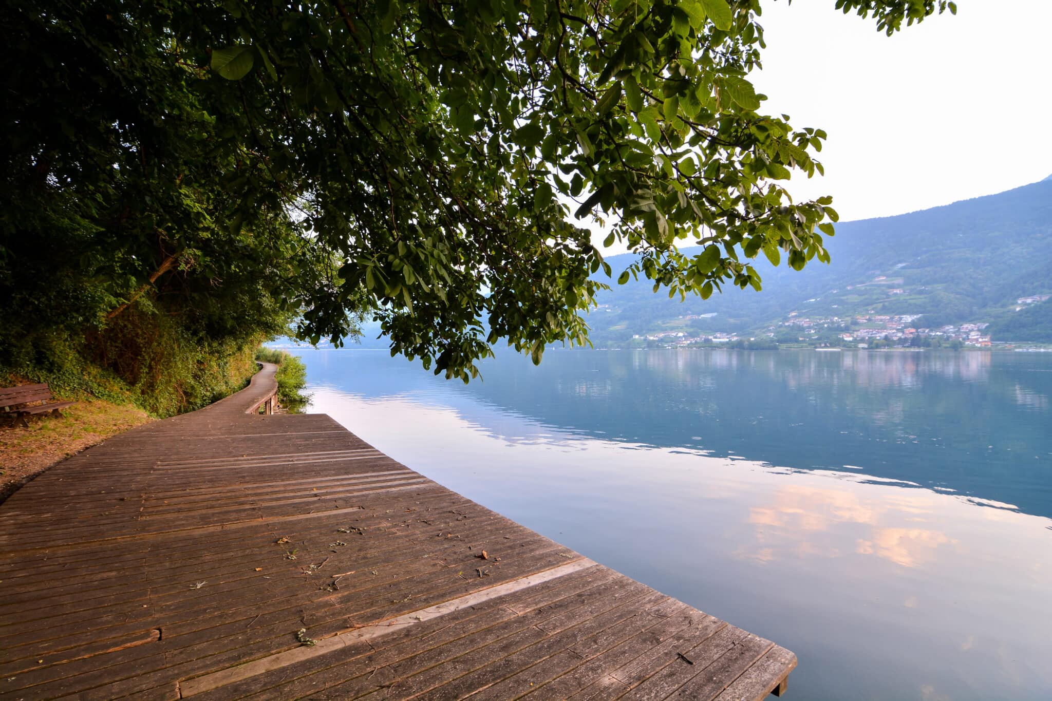 Promenade au bord du lac avec jetée et reflets.