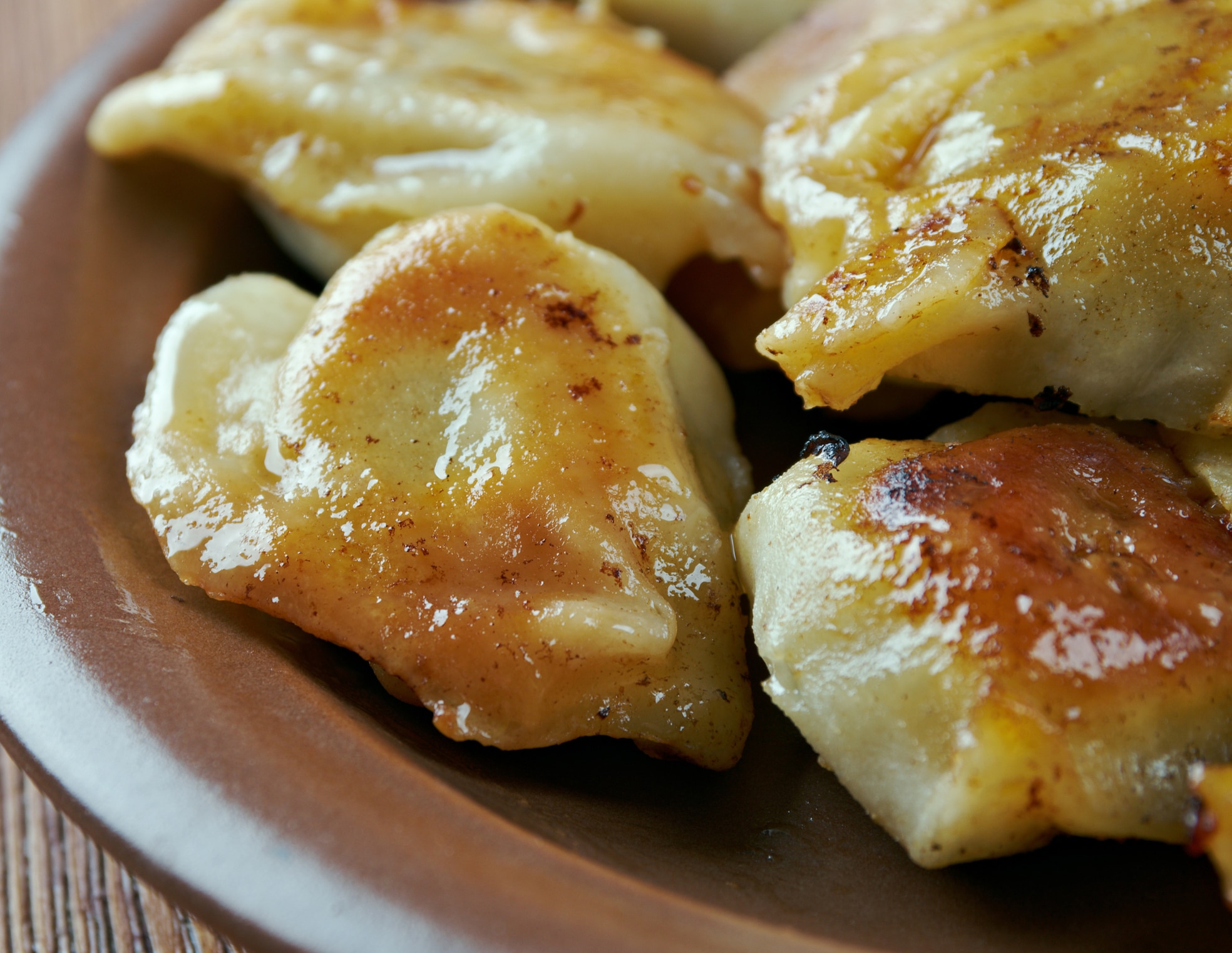 Raviolis dorés sur une assiette brune.