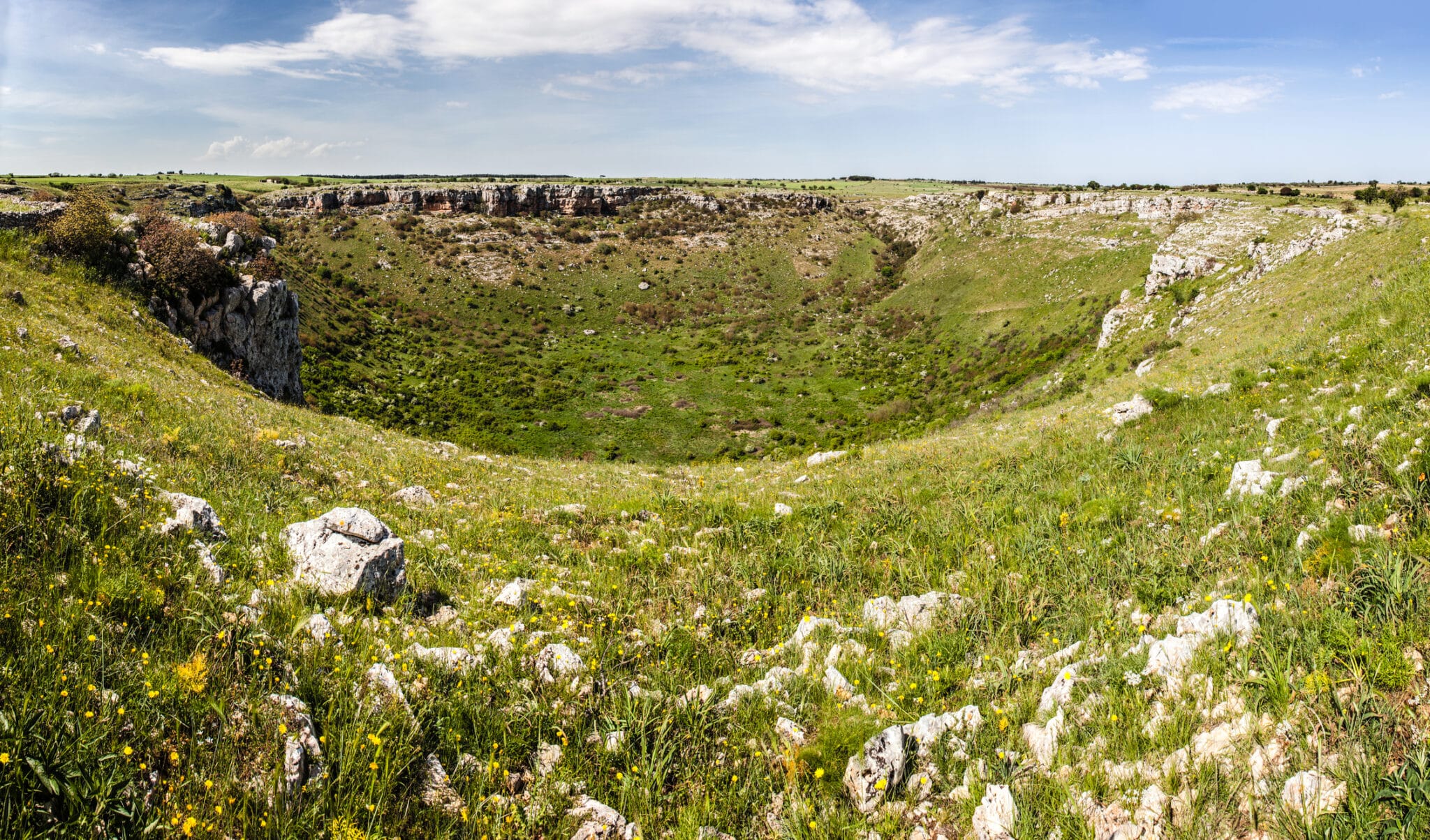 Paysage de collines verdoyantes avec des rochers et un ciel bleu.