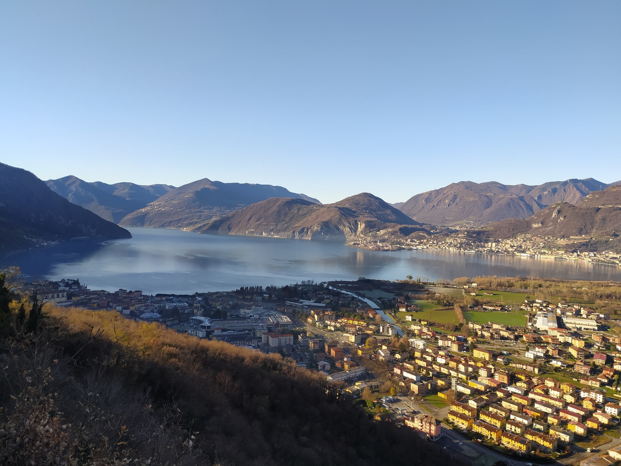 Vue panoramique sur le lac, les montagnes et les habitations.