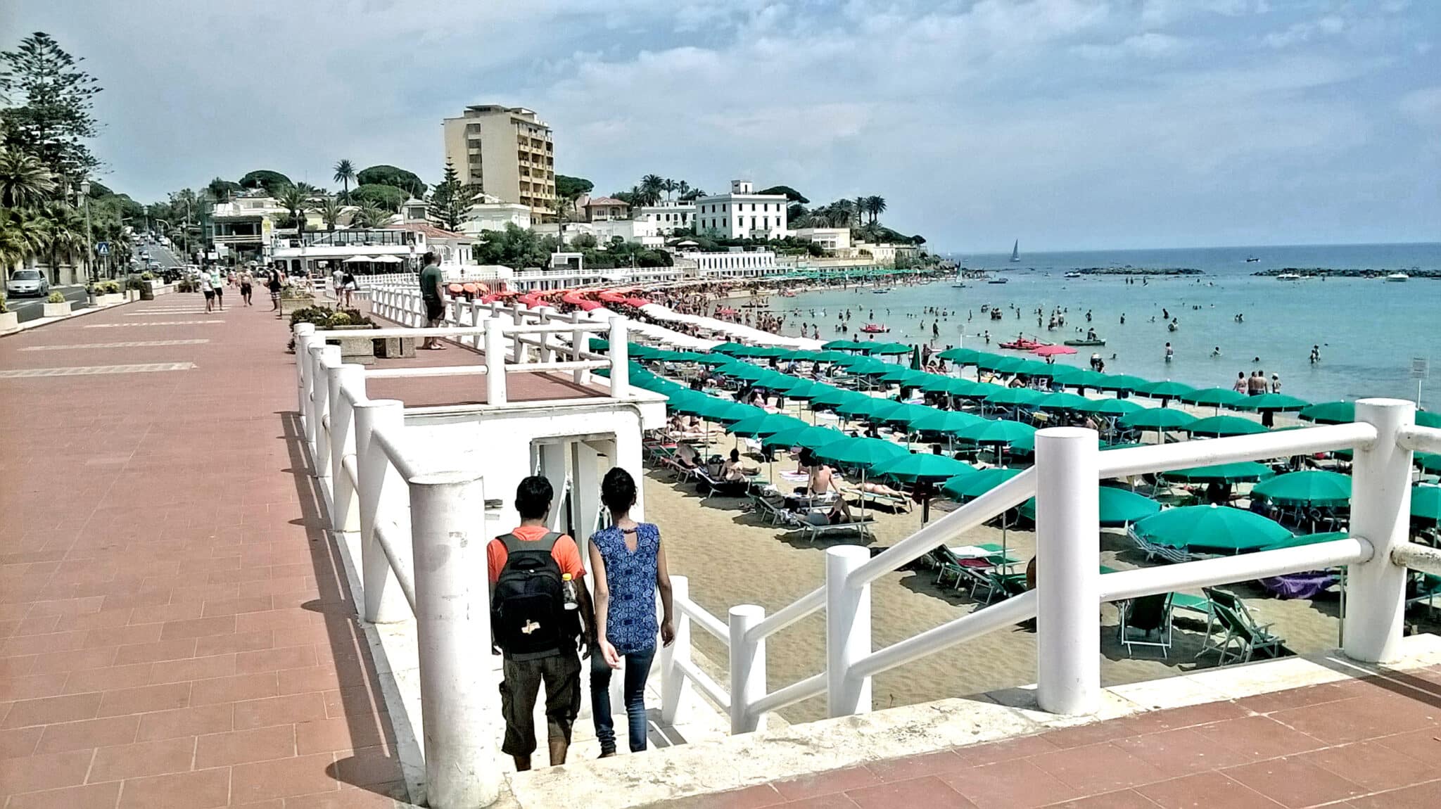 Plage bondée avec parasols et promenade.