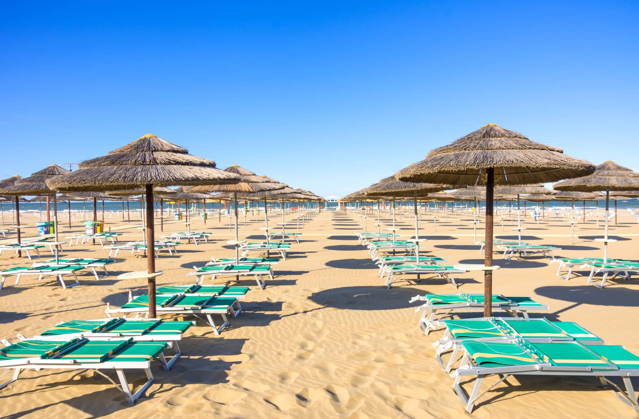 Plage de sable avec parasols et chaises longues.