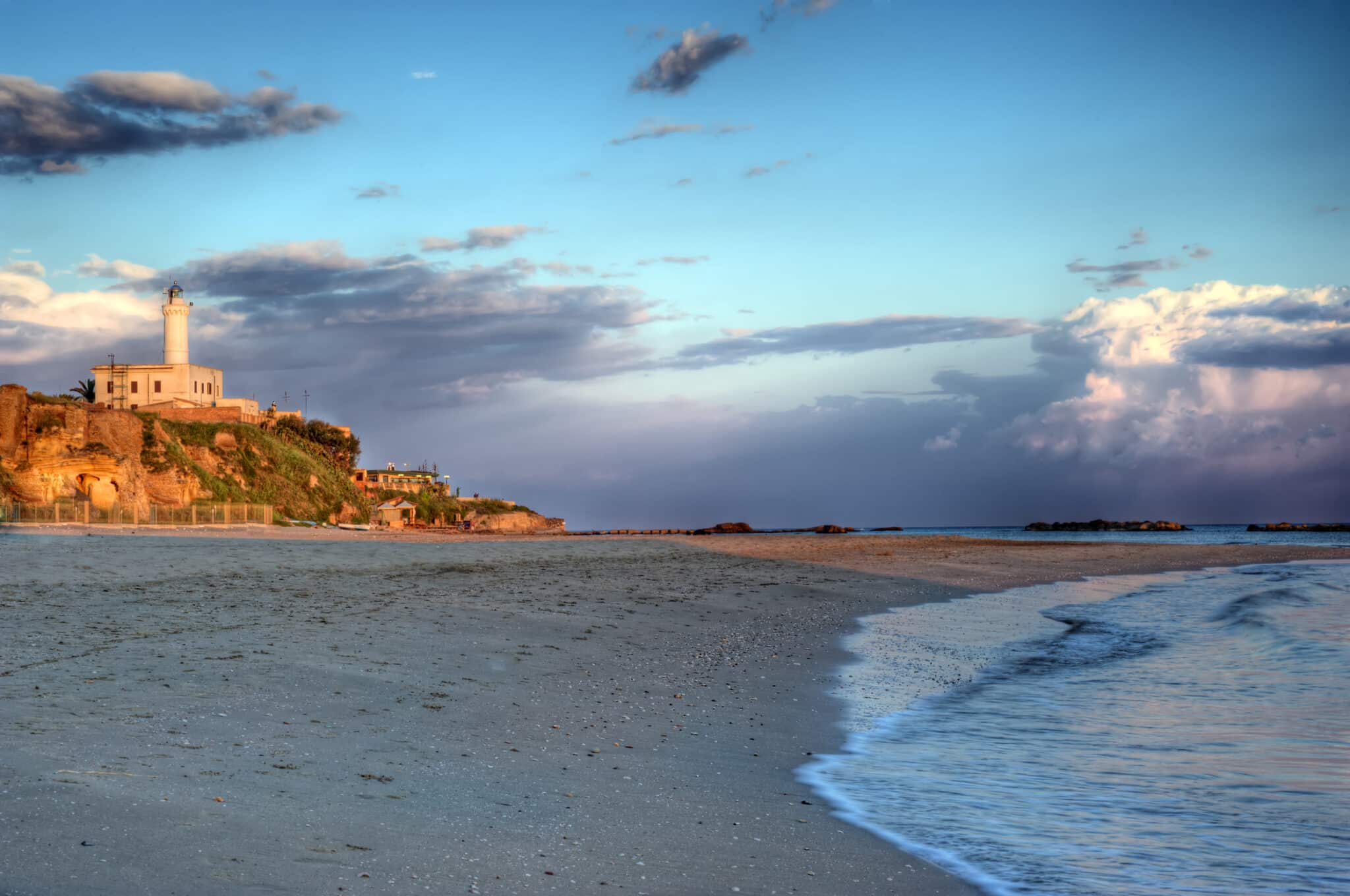 Faro su scogliera al tramonto.