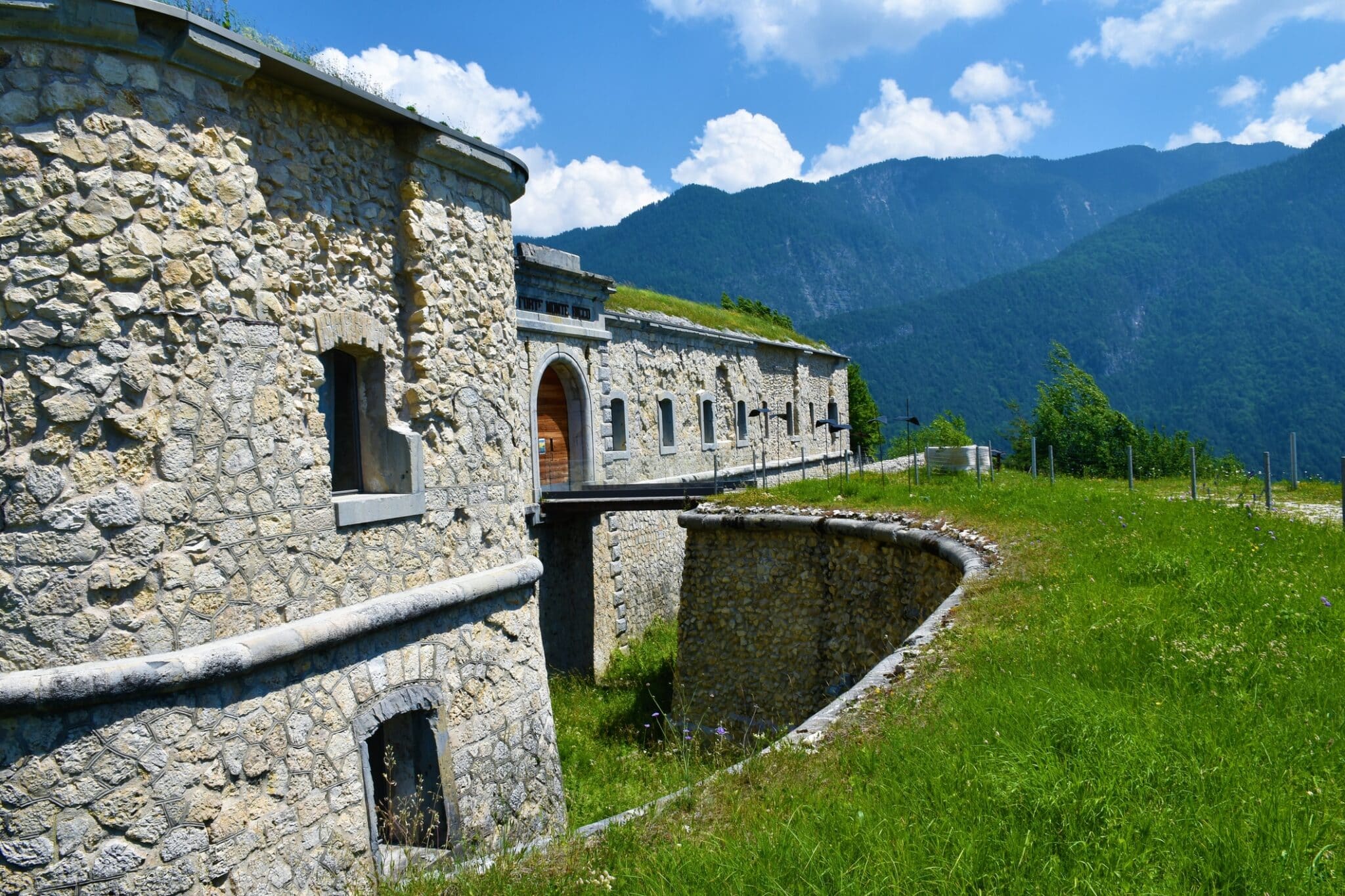 Historic fortress amidst green mountains under blue skies