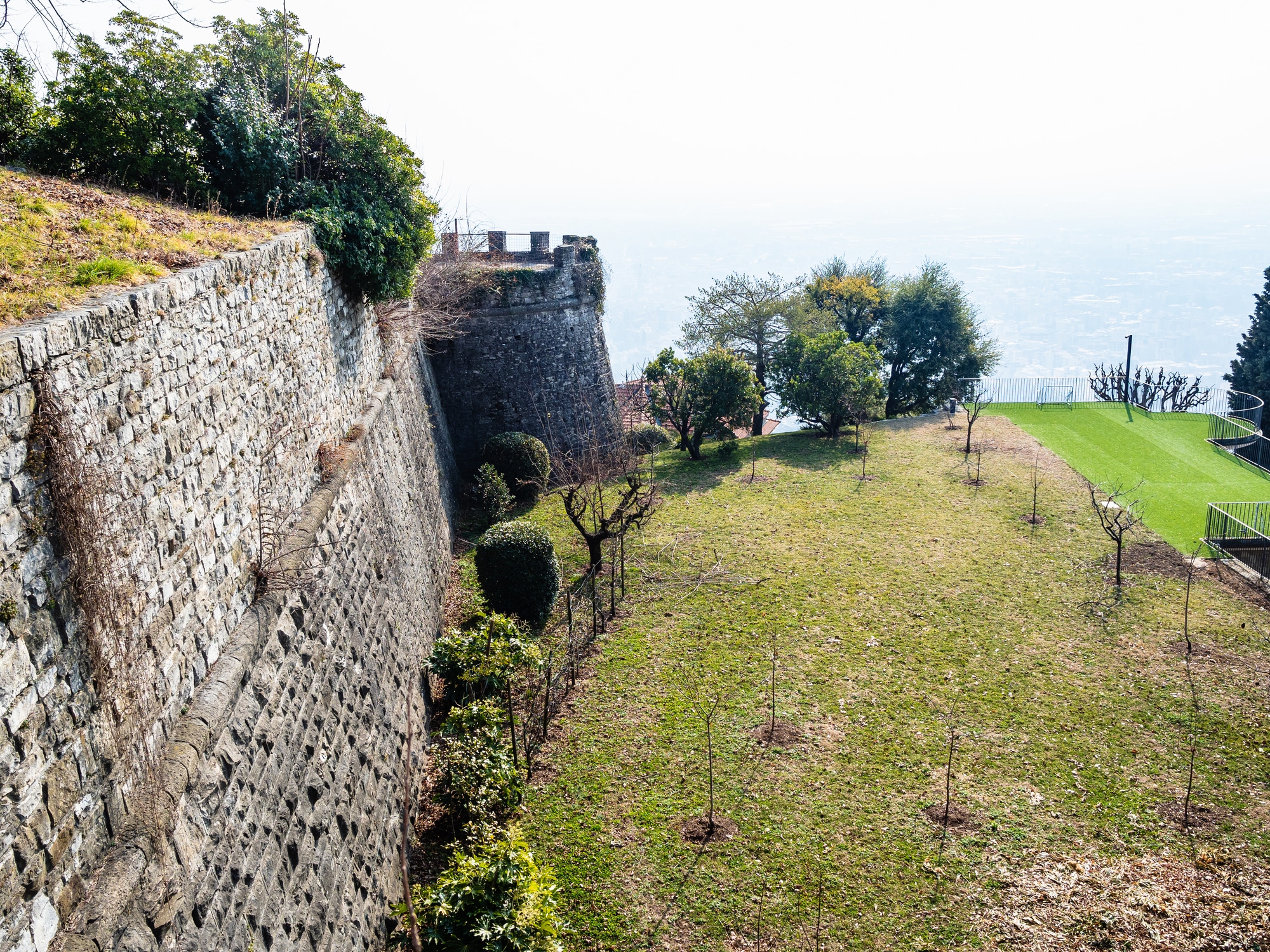 Fortification avec mur de pierre et espace vert.