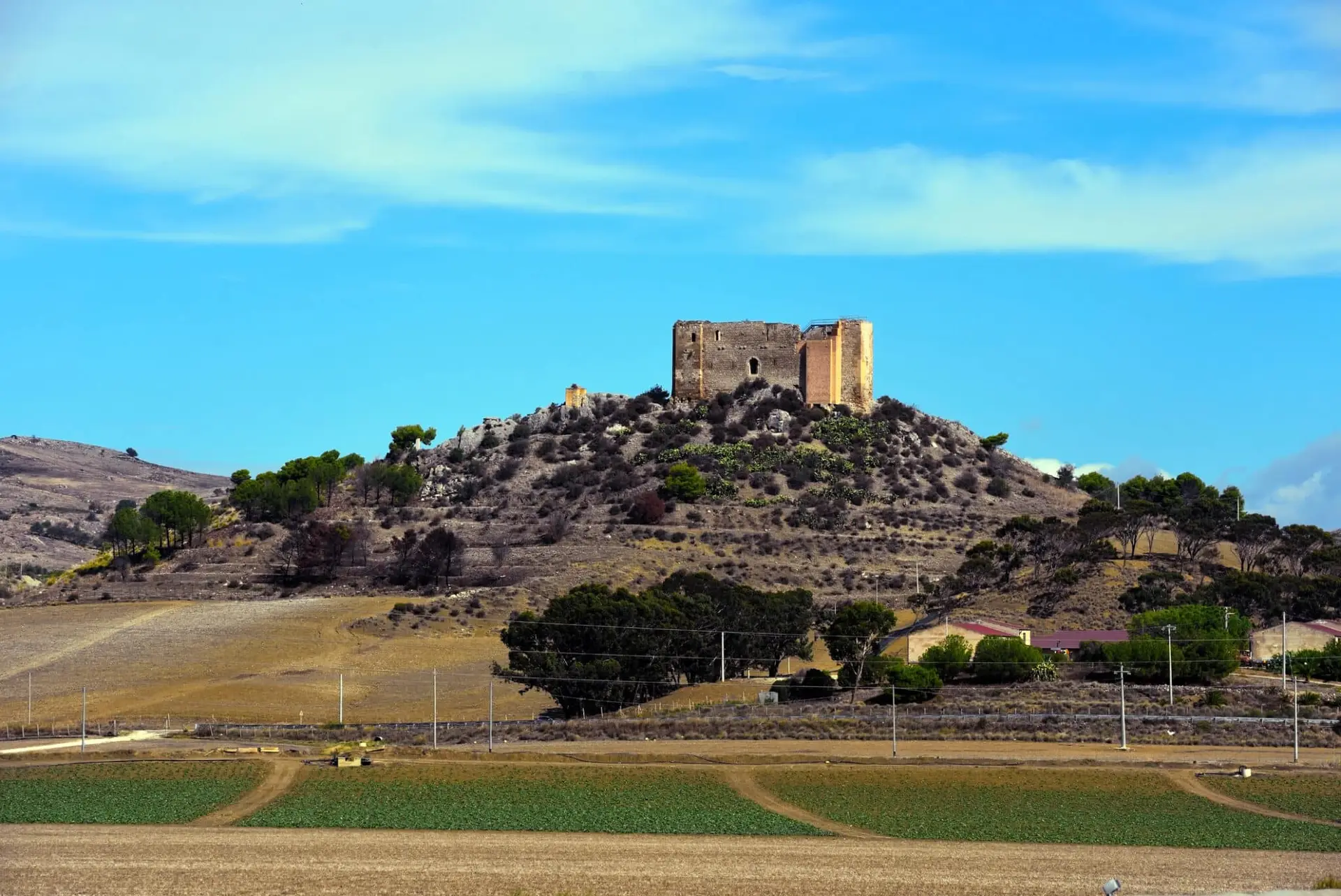 Castello antico su collina tra campi coltivati