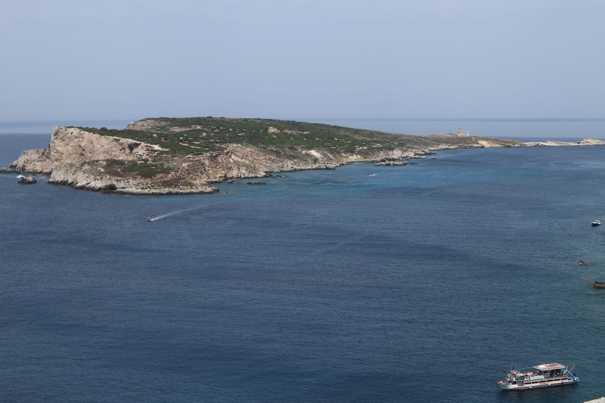 Isola rocciosa nel mare blu con barche