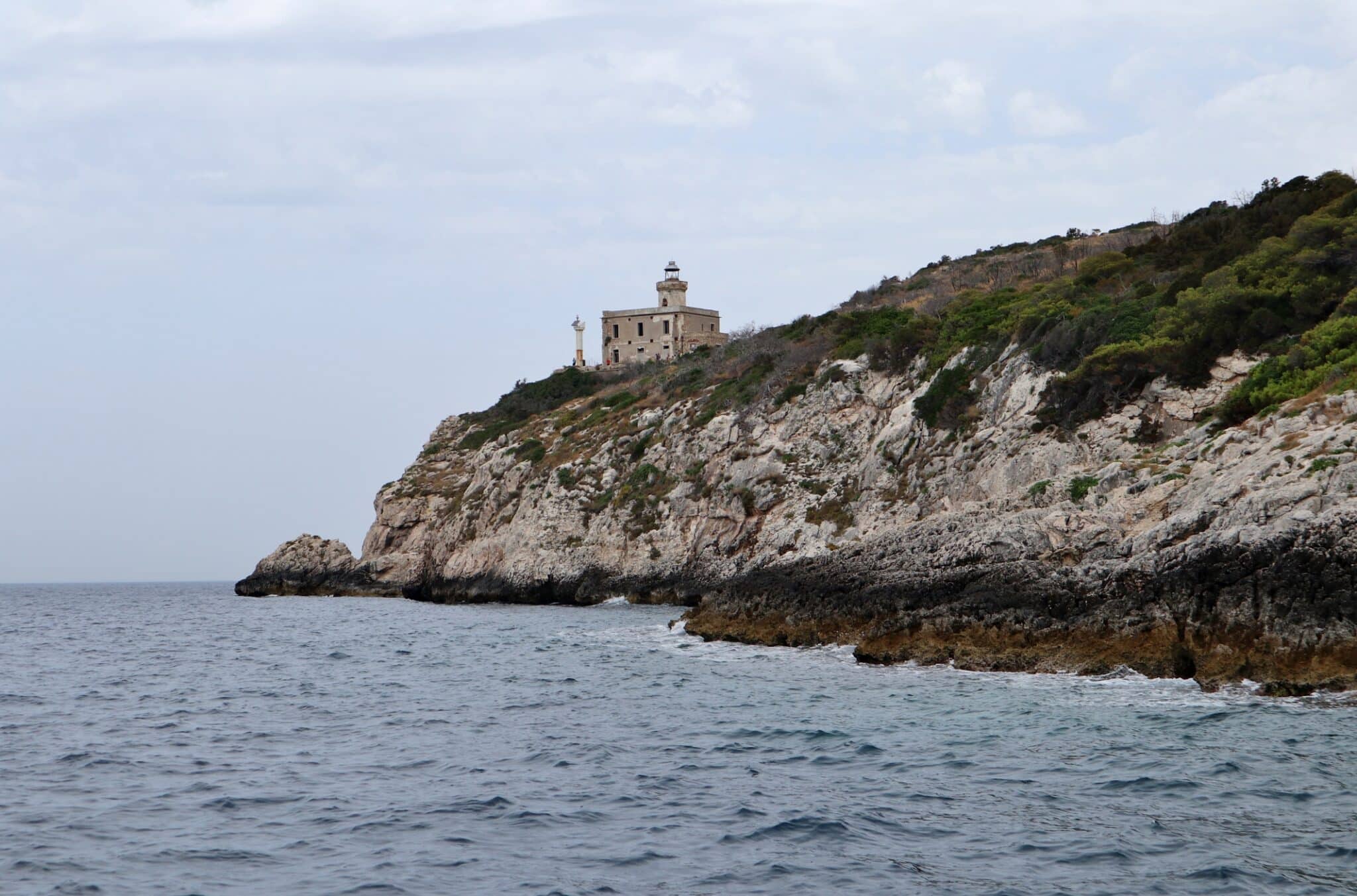 Faro su scogliera costiera, mare agitato